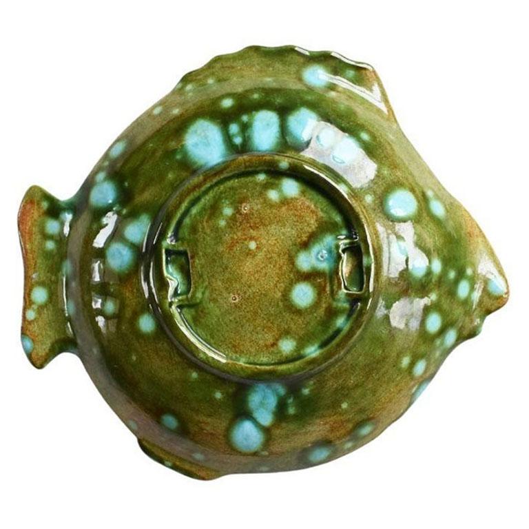 A small ceramic fish trinket dish or catchall. Perfect for a nightstand, coffee table, or foyer table, this colorful bowl will add a pop of color to any space. The interior of the bowl features textured scales, and a small mouth and eye. Its tail