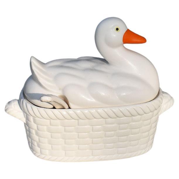 A pretty creamy white mallard duck tureen with ladle and cover. This would be an excellent serving dish for soups or gravy. The dish is glazed in white with an orange beak and black eyes. The top is removable and reveals an oval bowl decorated in a