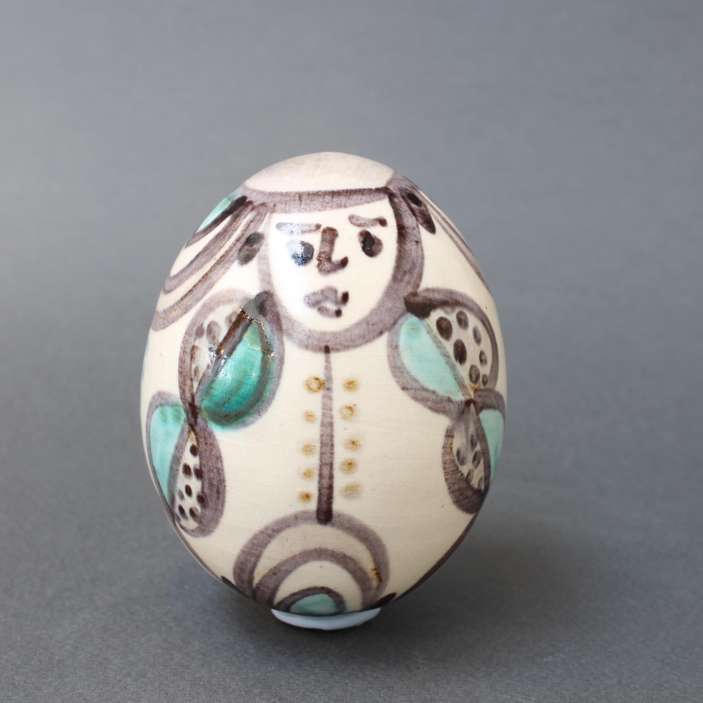 Oeuf vintage en céramique de l'Atelier Madoura, Vallauris, France (circa 1960s). Cette figurine en céramique de la taille d'un œuf est peinte d'un homme stylisé en costume avec un sourire sur le visage. Il s'agit d'une œuvre peinte simplement mais