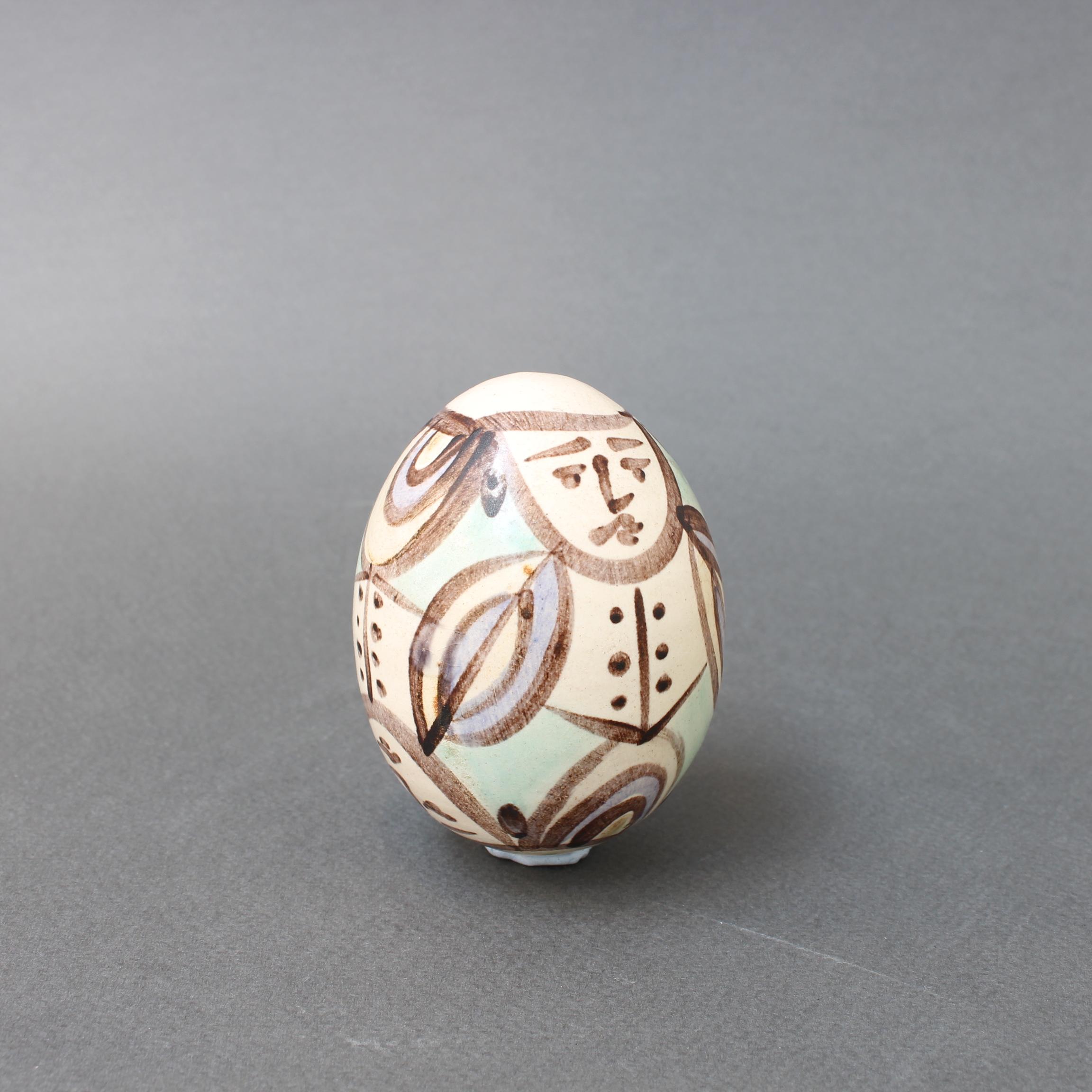 Vintage ceramic egg figure from Atelier Madoura, Vallauris, France (circa 1960s). This egg-sized ceramic figure is painted with a stylized suited man with a frown on his face. It is a simply but elegantly painted work with many charms and would