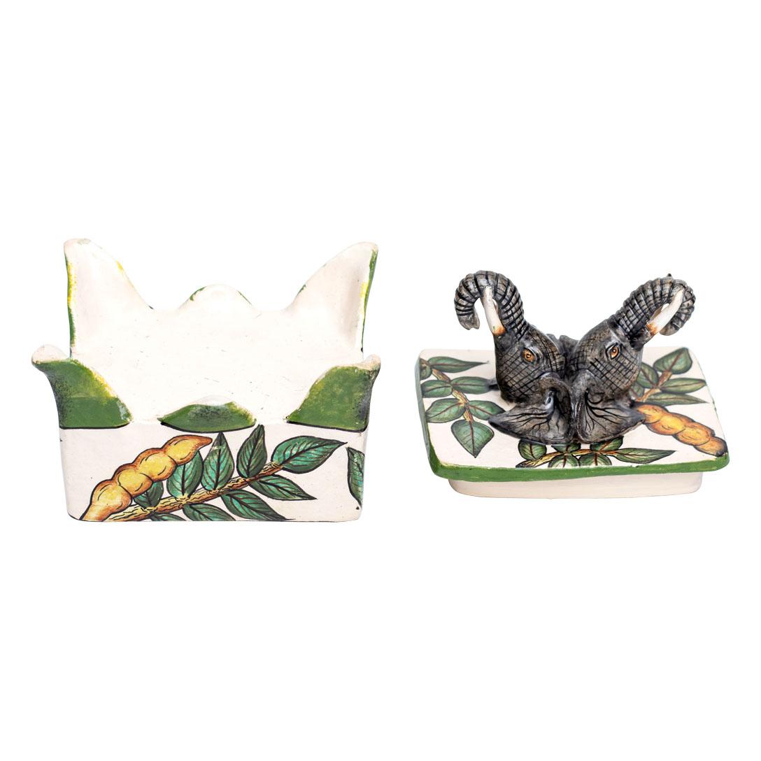 This charming ceramic Elephant jewelry box, crafted at Imvelo Natural Art in South Africa, stands 5 inches tall with dimensions of 4 inches in both length and width. Hand-sculpted by Bennet Zondo and meticulously hand-painted by Samukelo Gumede, it