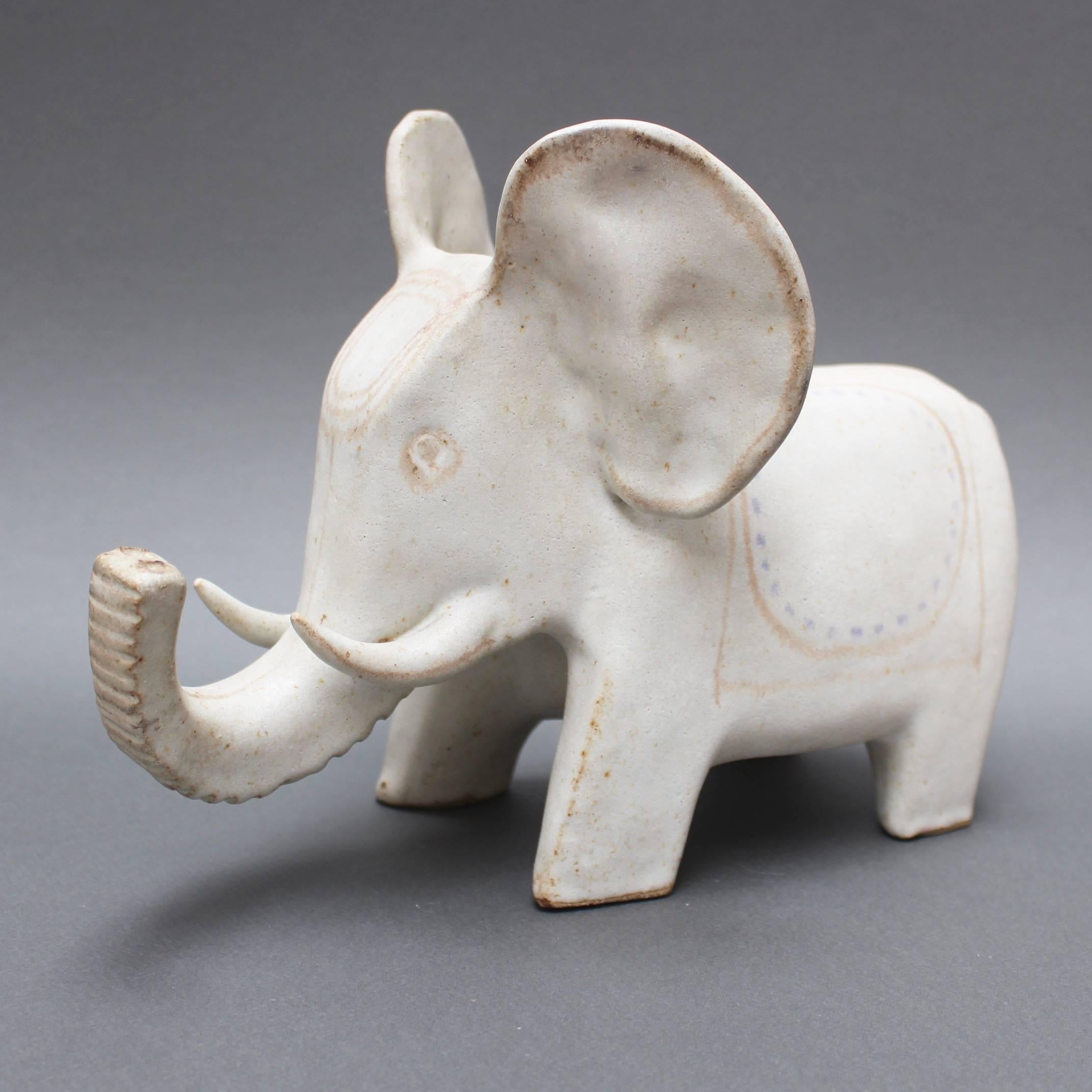 Ceramic Indian motif white elephant by Bruno Gambone (circa 1970s). This is an uplifting ceramic white elephant with an Indian-style blanket and headdress, large whimsical ears and tusks in Gambone's signature chalk-white. Light brown and blue