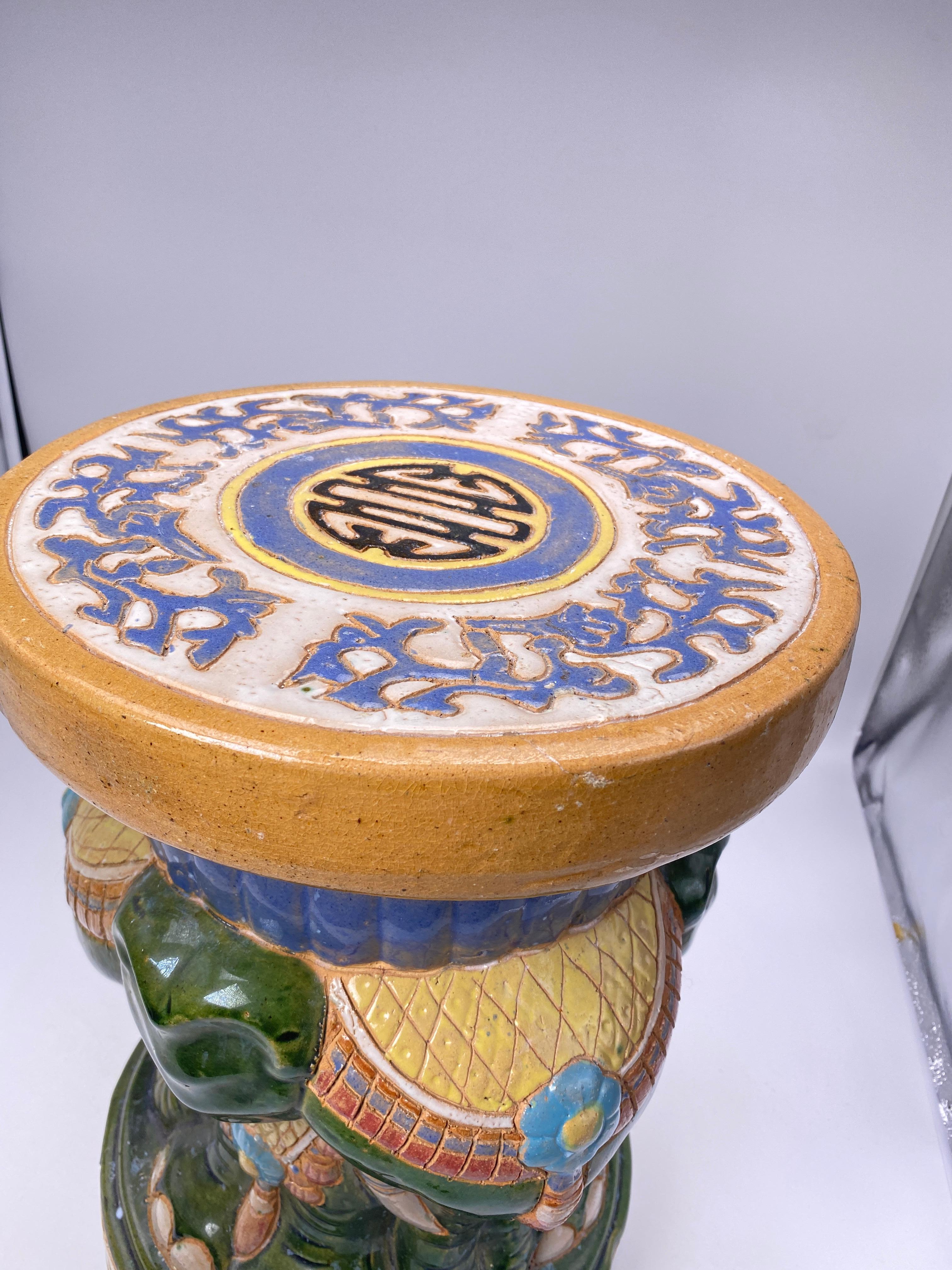 Ceramic elephant, in green and purple colors. It was made in China in the 20th century, it is hand painted. This object can also be used as a stool, table or plant holder. It can be used both indoors and outdoors.