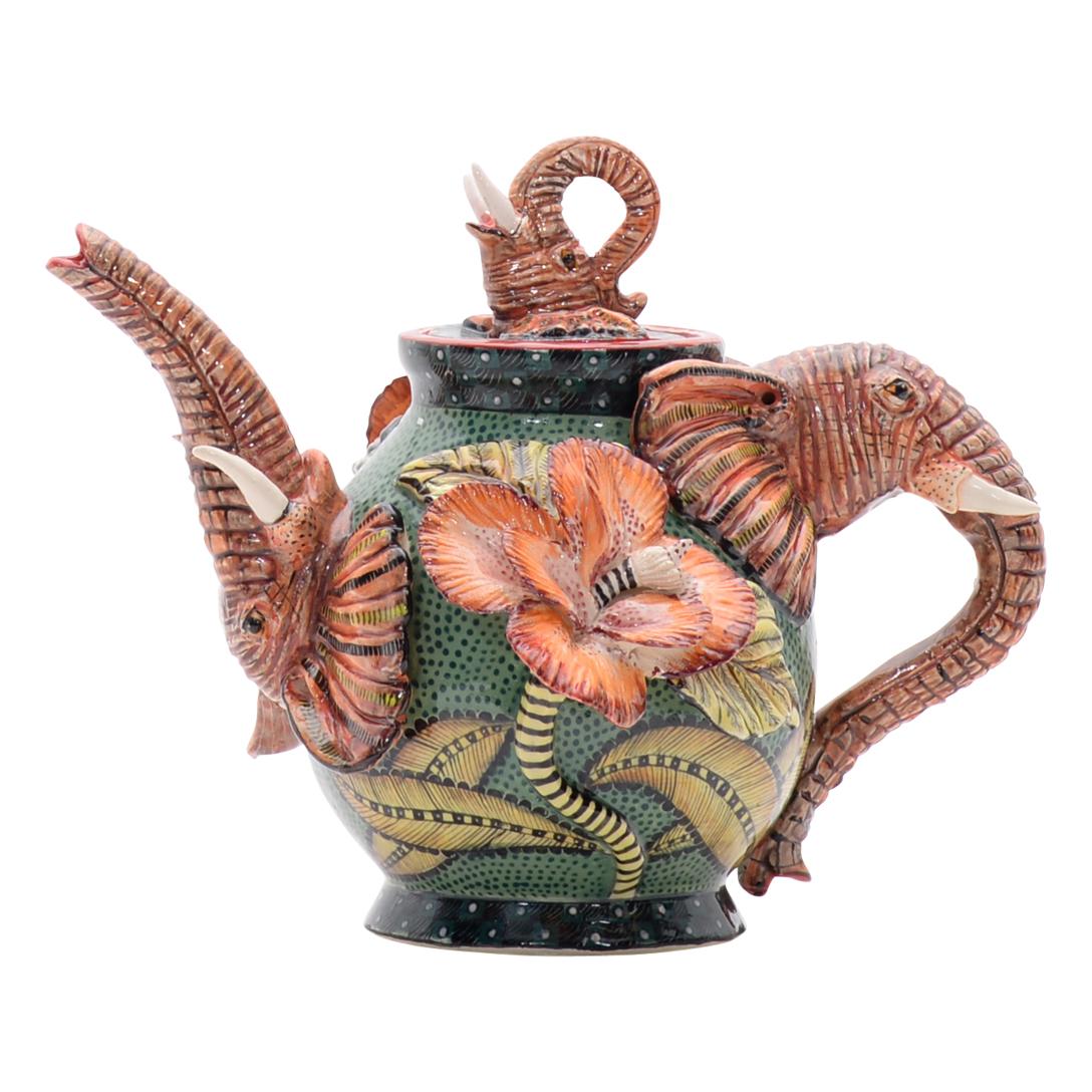 The Elephant Teapot by Love Art Ceramics is a masterpiece combining craftsmanship and cultural symbolism. Hand-sculpted by Sondelani Ntshalintshali and meticulously hand-painted by Zinhle Nene in South Africa, it stands 9 inches tall, with