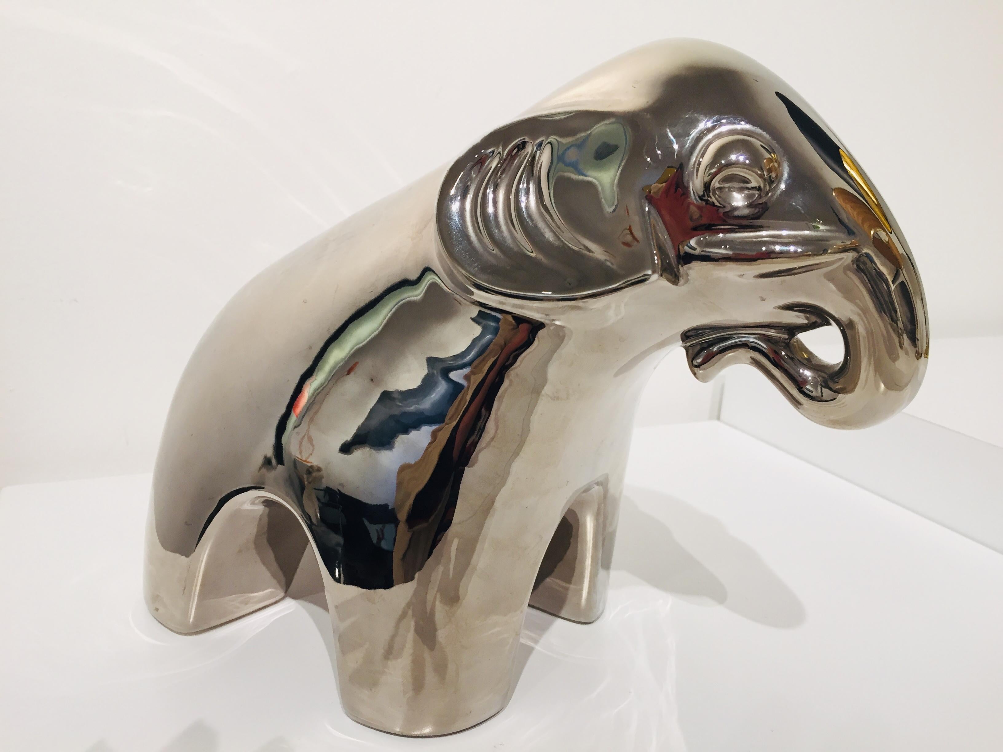 Éléphant contemporain en céramique avec finition miroir. La couleur varie légèrement en fonction de la lumière. Une certaine usure est légèrement visible sur les deux oreilles.