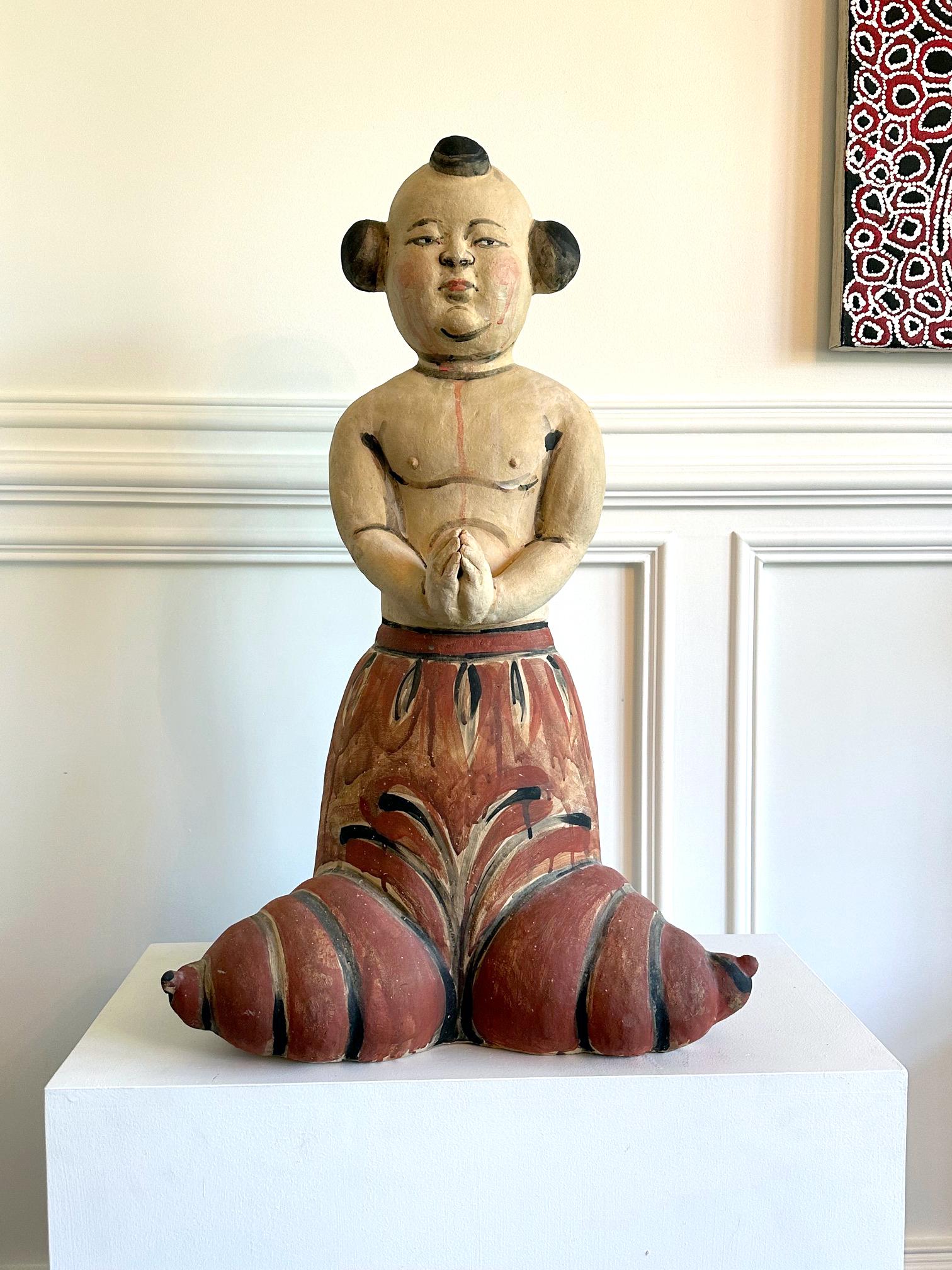 A large figurative ceramic sculpture entitled by Akio Takamori (1950 - 2017) created in 2004. Stoneware with hand-painted surface, the sculpture depicts a half-naked standing boy figure with his hands in praying position.   His berobed lower body,