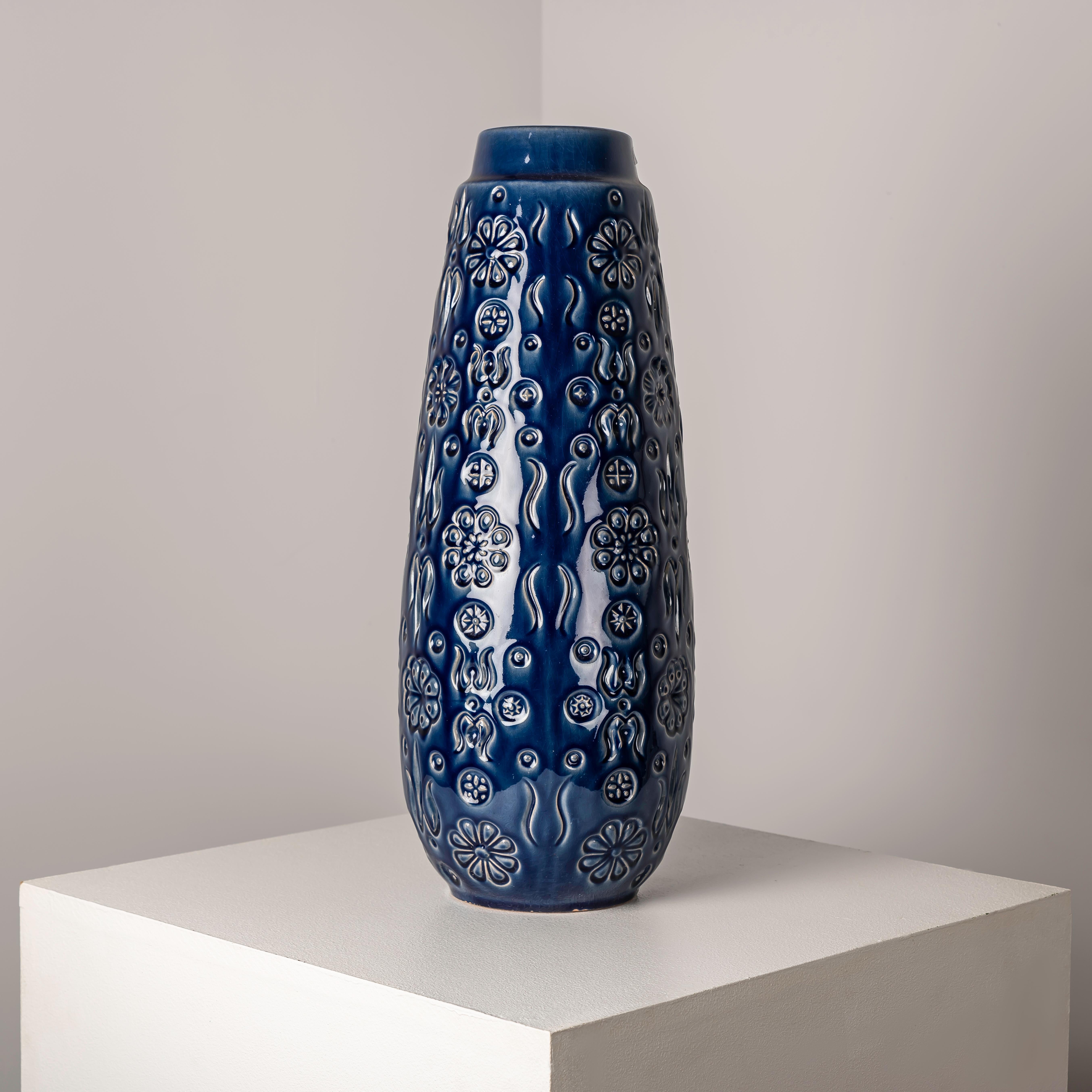 Investire in questo vaso floreale in ceramica della Germania Ovest, risalente agli anni '60 e caratterizzato da un caratteristico smalto blu, offre un'opportunità unica di possedere un pezzo di storia del design di metà secolo che fonde senza sforzo