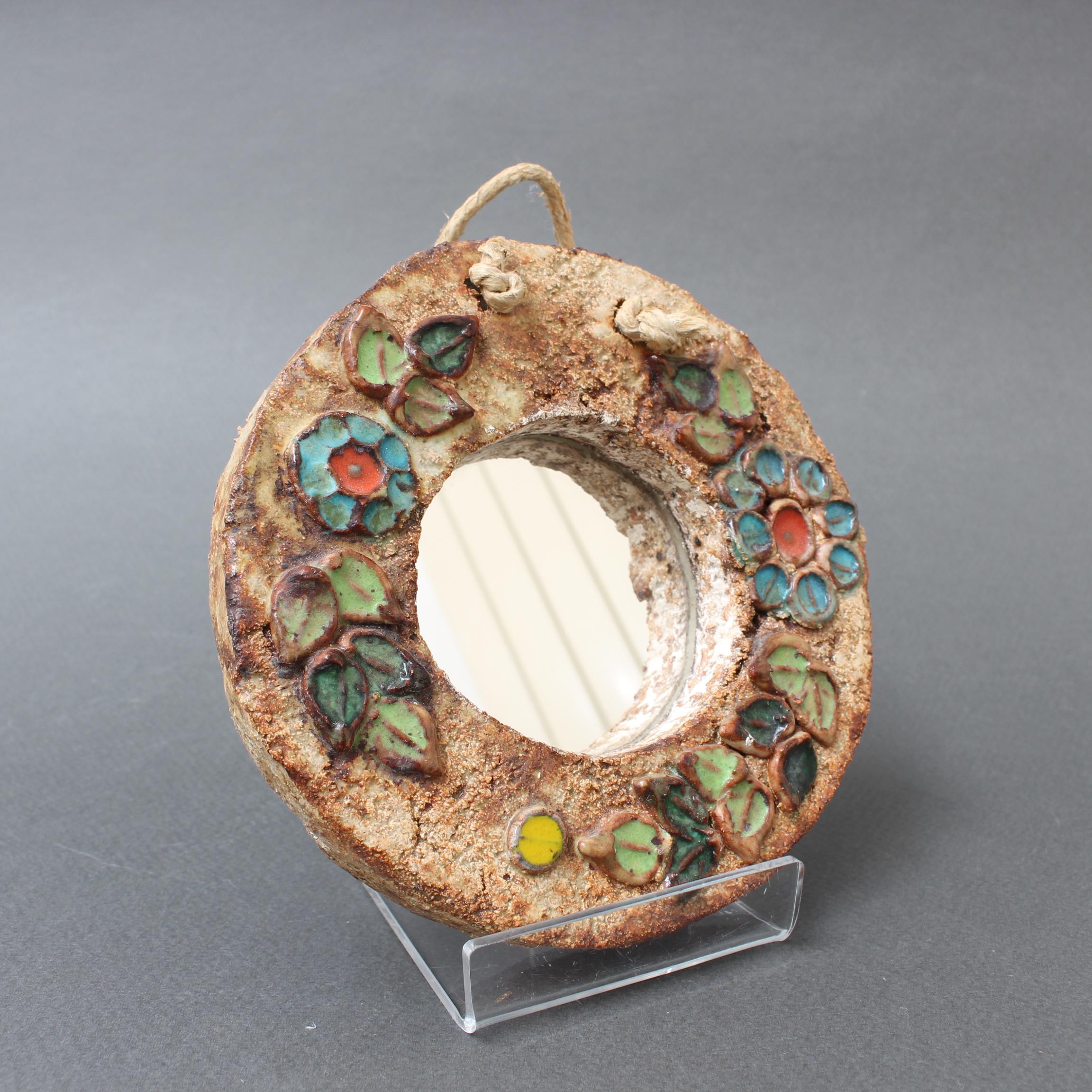 Small ceramic flower-motif mirror with glazed leaves by La Roue, Vallauris, France, (circa 1960s). A charming, decorative mirror with rustic but colorful details surrounding the circular mirror. In good vintage condition commensurate with its age