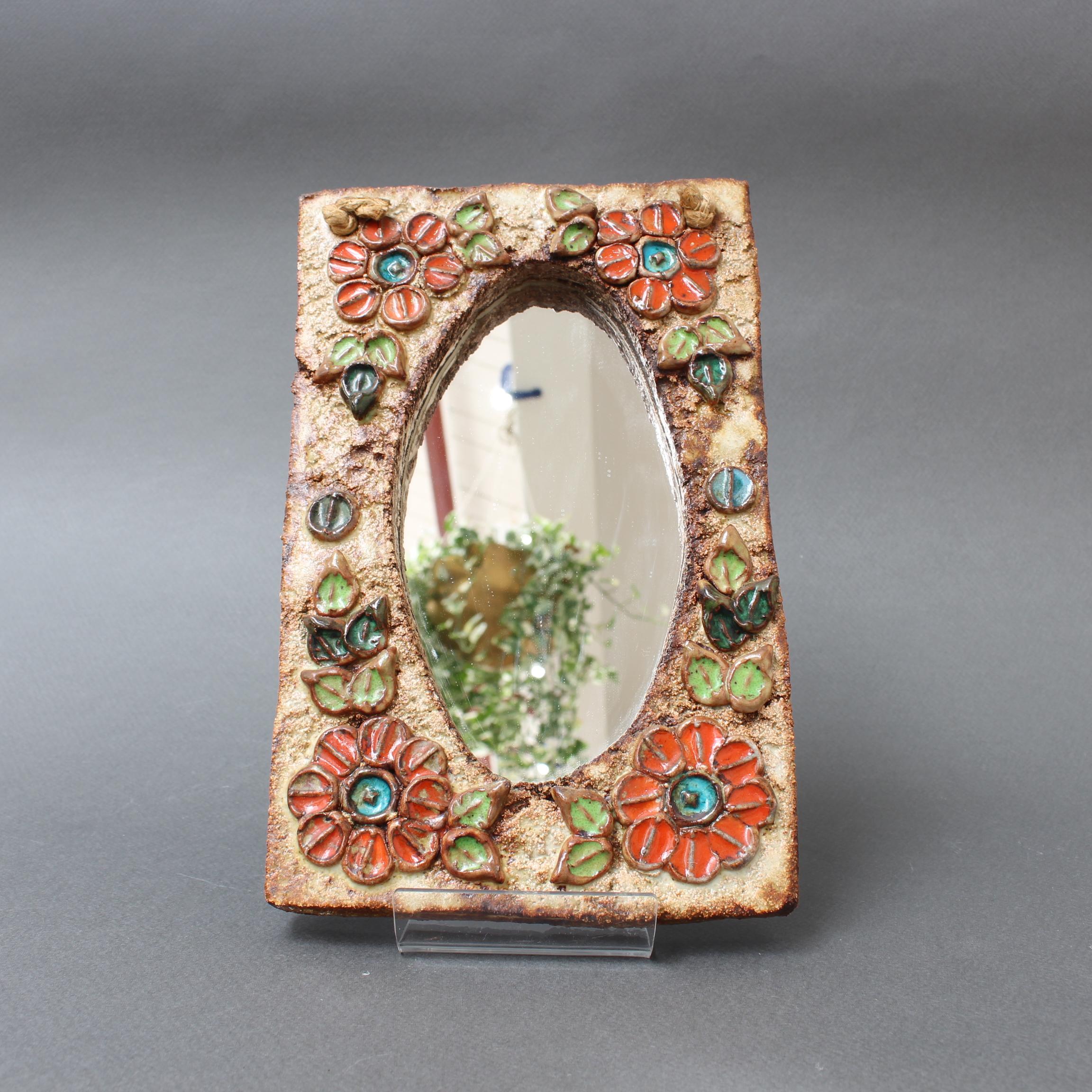 Ceramic flower-motif wall mirror with glazed leaves by La Roue, Vallauris, France (circa 1960s). A charming, decorative diminutive piece with rustic but colourful details surrounding the stylish oval glass. In good vintage condition showing