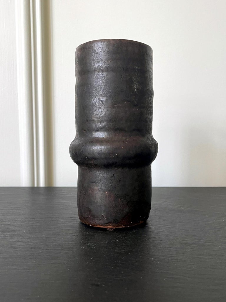 A ceramic vase by American artist and studio potter Beatrice Wood (1893-1998). The piece, circa 1980s, is of a columnar form with a small bulged-out ring around midbody. Highly geometrical and modern in its minimalistic appearance, the vase was