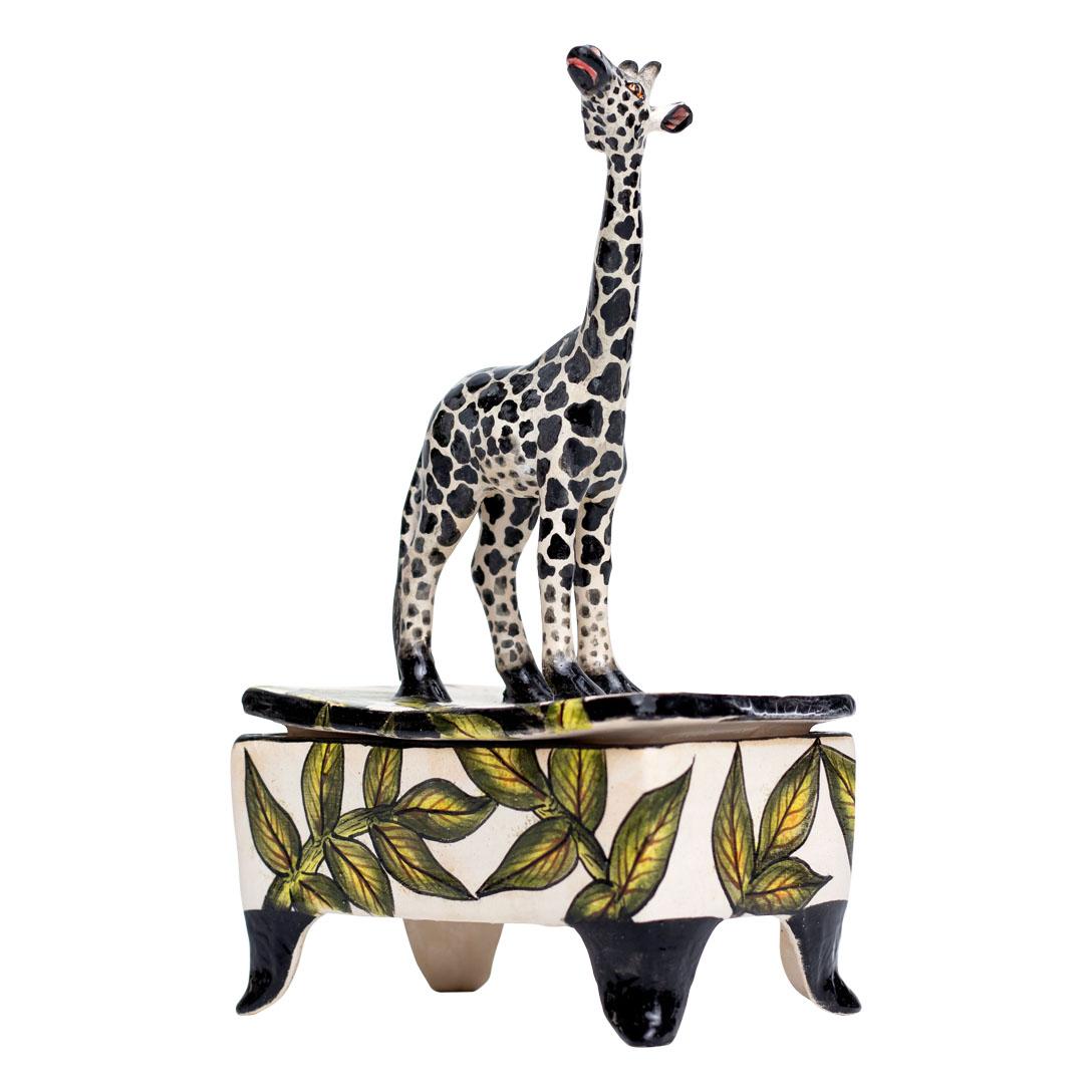 Presenting the Ceramic Giraffe Jewelry Box, an enchanting creation by Imvelo Natural Art, South Africa. Sculpted by Bennet Zondo, hand-painted by Samukelo Gumede, and designed by Senzo Duma, this piece stands 8 inches high, 5 inches long, and 3