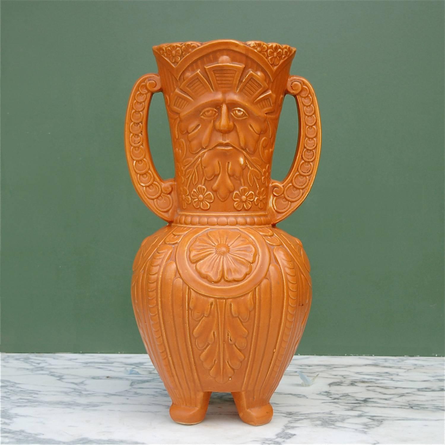 Tall, ceramic vase, urn or vessel with a raised relief of the Green Man. The motif of the Green Man celebrates the earliest archetype of the Forest God, the spirit of all that things green. Here it's represented by a face surrounded by and made from
