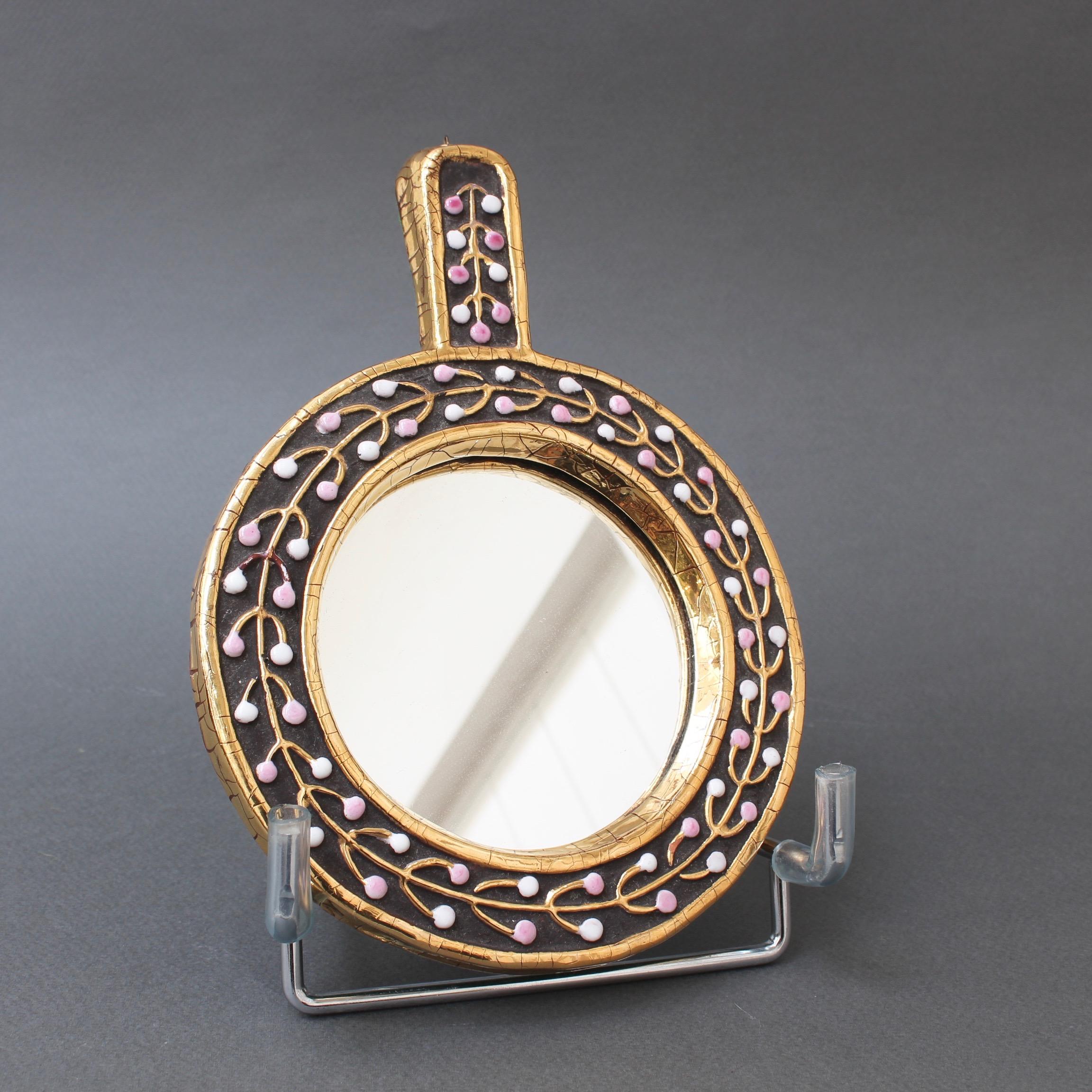 Ceramic hand mirror with flower bud motif by Mithé Espelt, circa 1960s. An elegant piece of decorative art consisting of a lustrous gold craquelure outer and inner frame. Between the craquelure is chocolate-brown ceramic with a gold flower bud motif