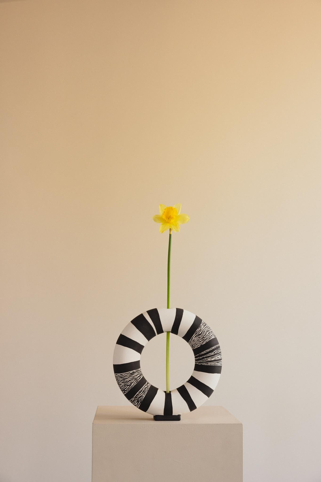 The Vacuum Vase is a remarkable ceramic piece that brings a story of artistry and family into every curve and brushstroke. This hand-painted black and white vase is crafted through a special mother-daughter collaboration, combining their unique