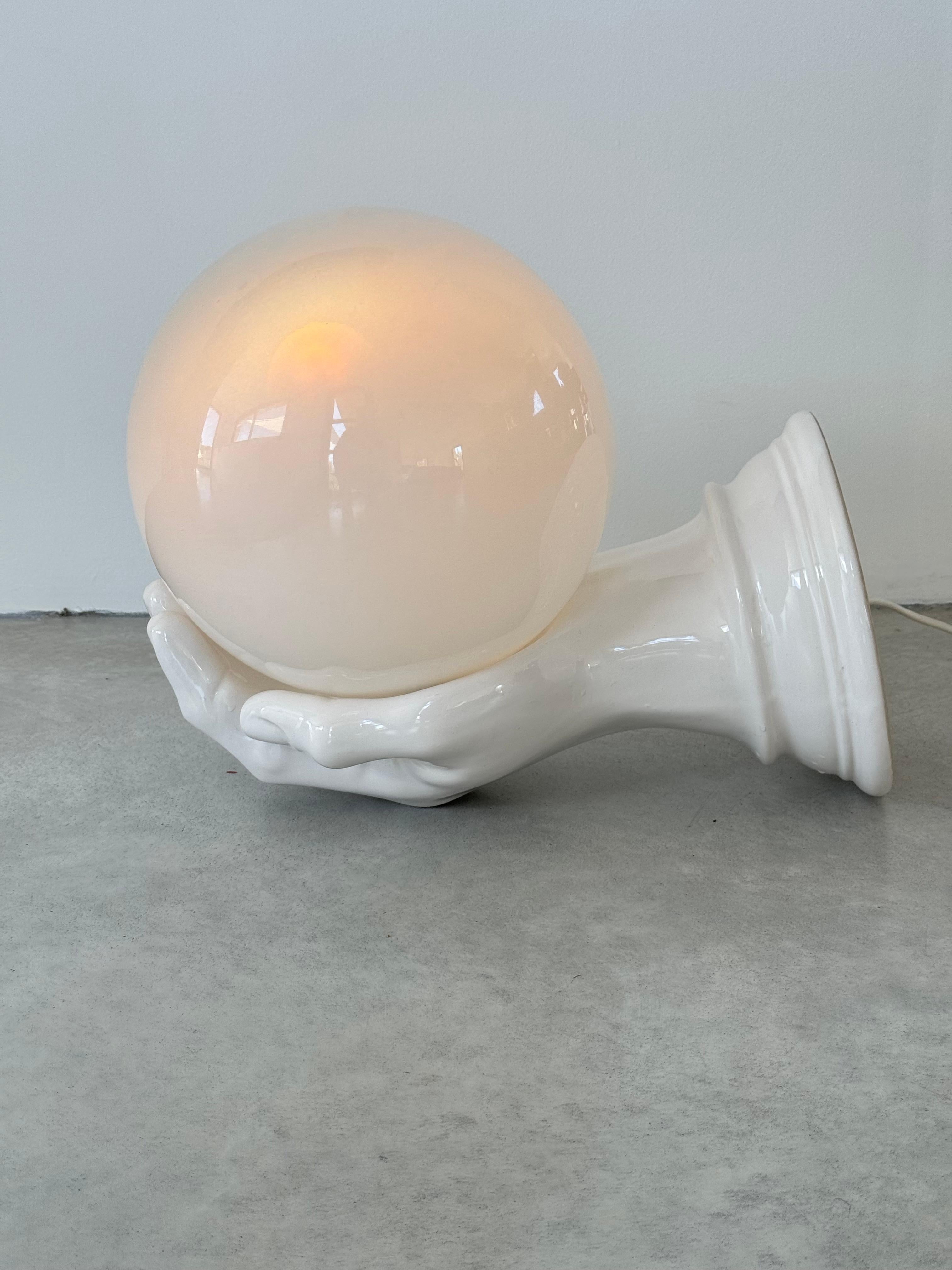 Huge ceramic wall light in the shape of a left hand.

Extremely rare with this large size

An opalescent Murano glass globe (diameter 9.8'') is placed in the palm of the hand.
The lamp attaches to the wall. There are two fixing holes for perfect