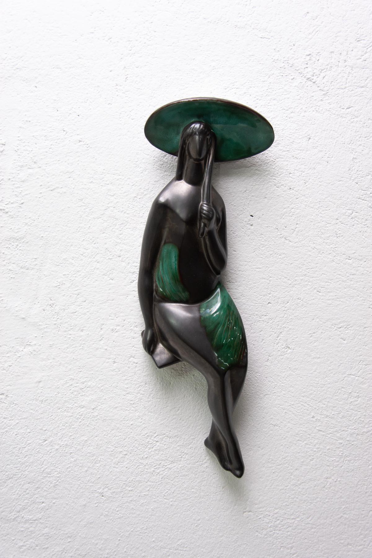 Ceramic hanging sculpture Girls with a parasol designed by Czechoslovak artist Jitka Forejtová. Made in 1960s. The sculpture is made of ceramics with green-black glaze. There is a hole for hanging from behind.
This minimalist design of the