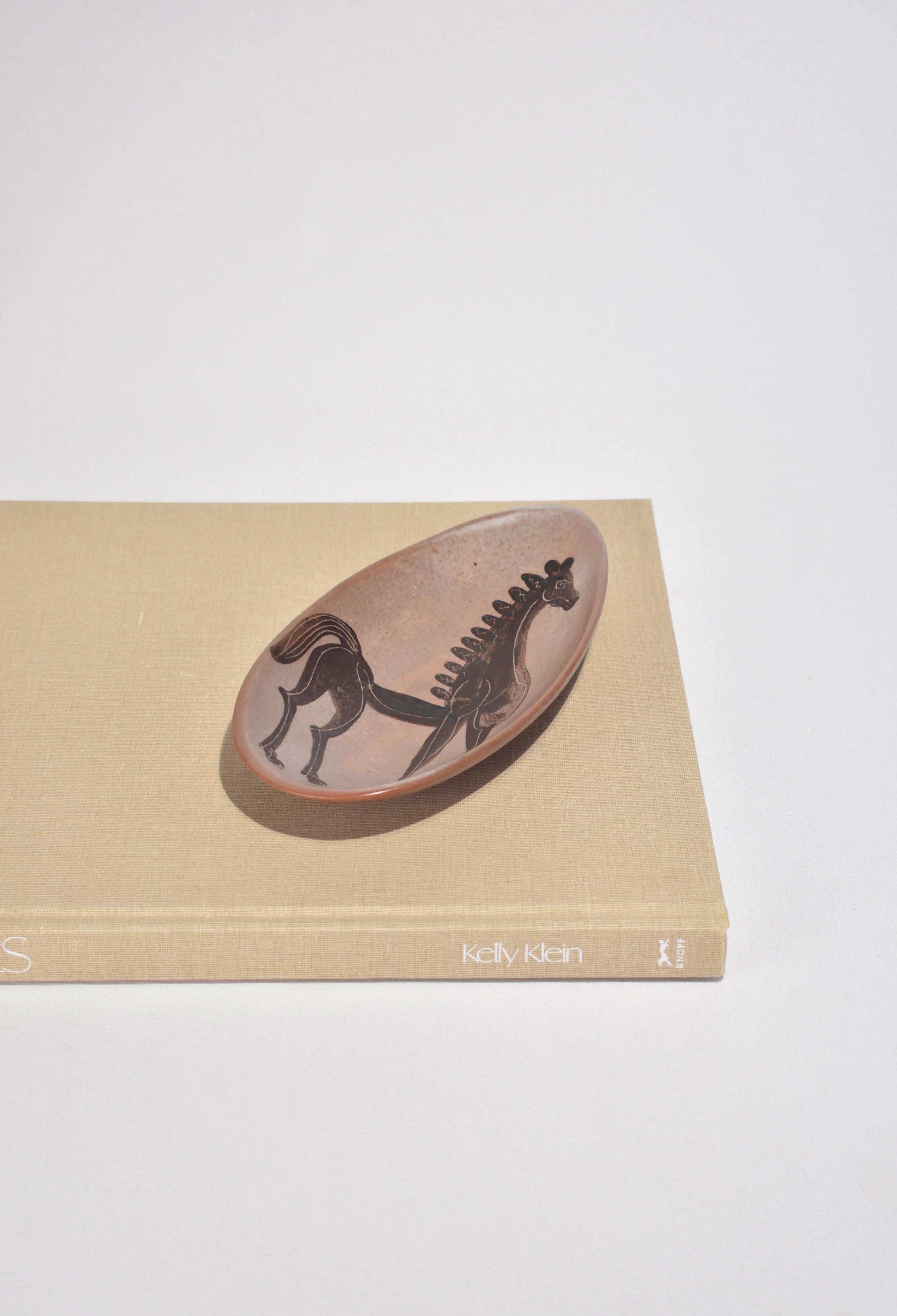 Plat en céramique de forme ovale avec un motif de cheval peint, signé sur la base.