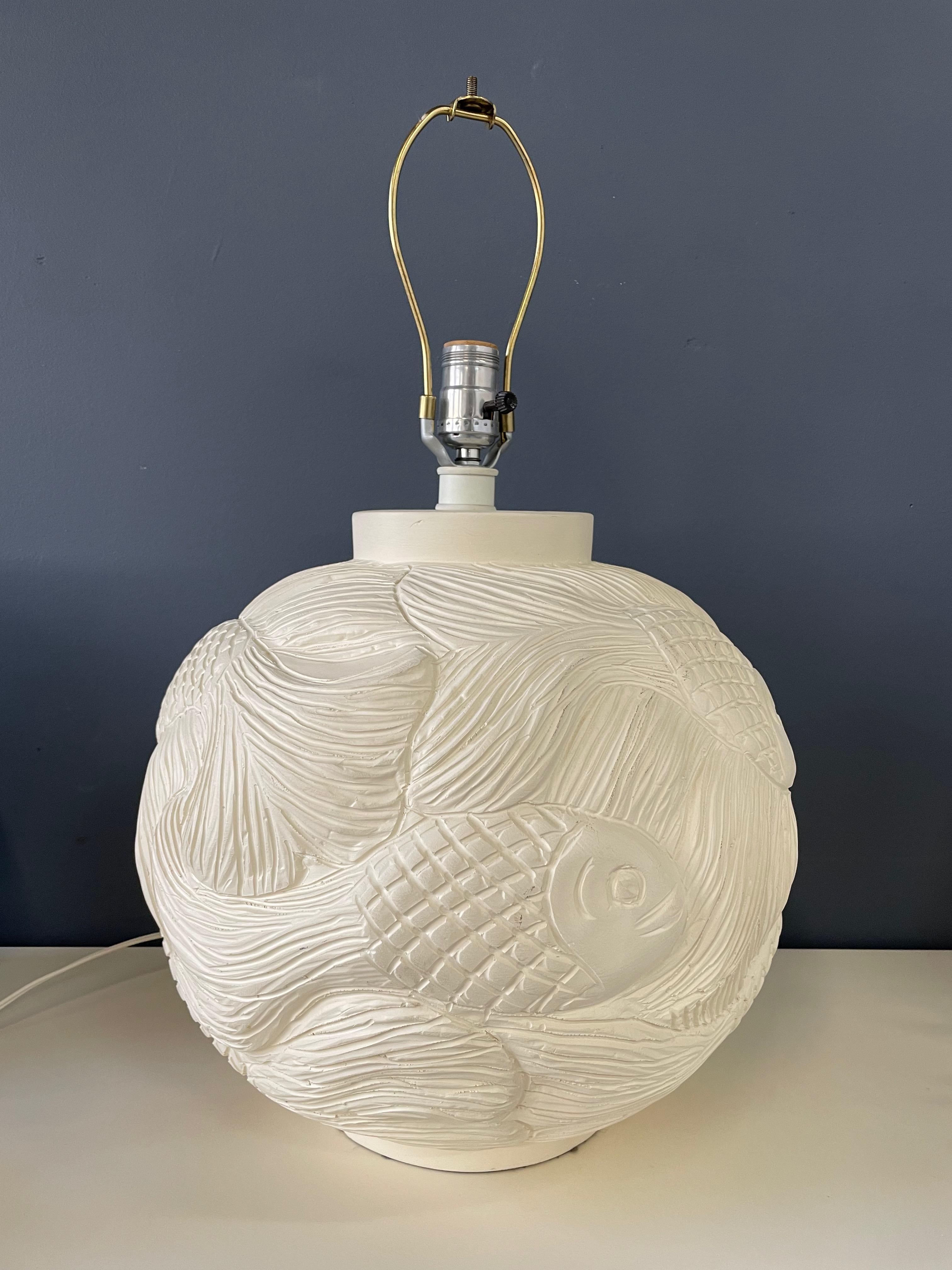 A beautiful hand crafted lamp with a pattern of swimming fish in a deeply incised method.