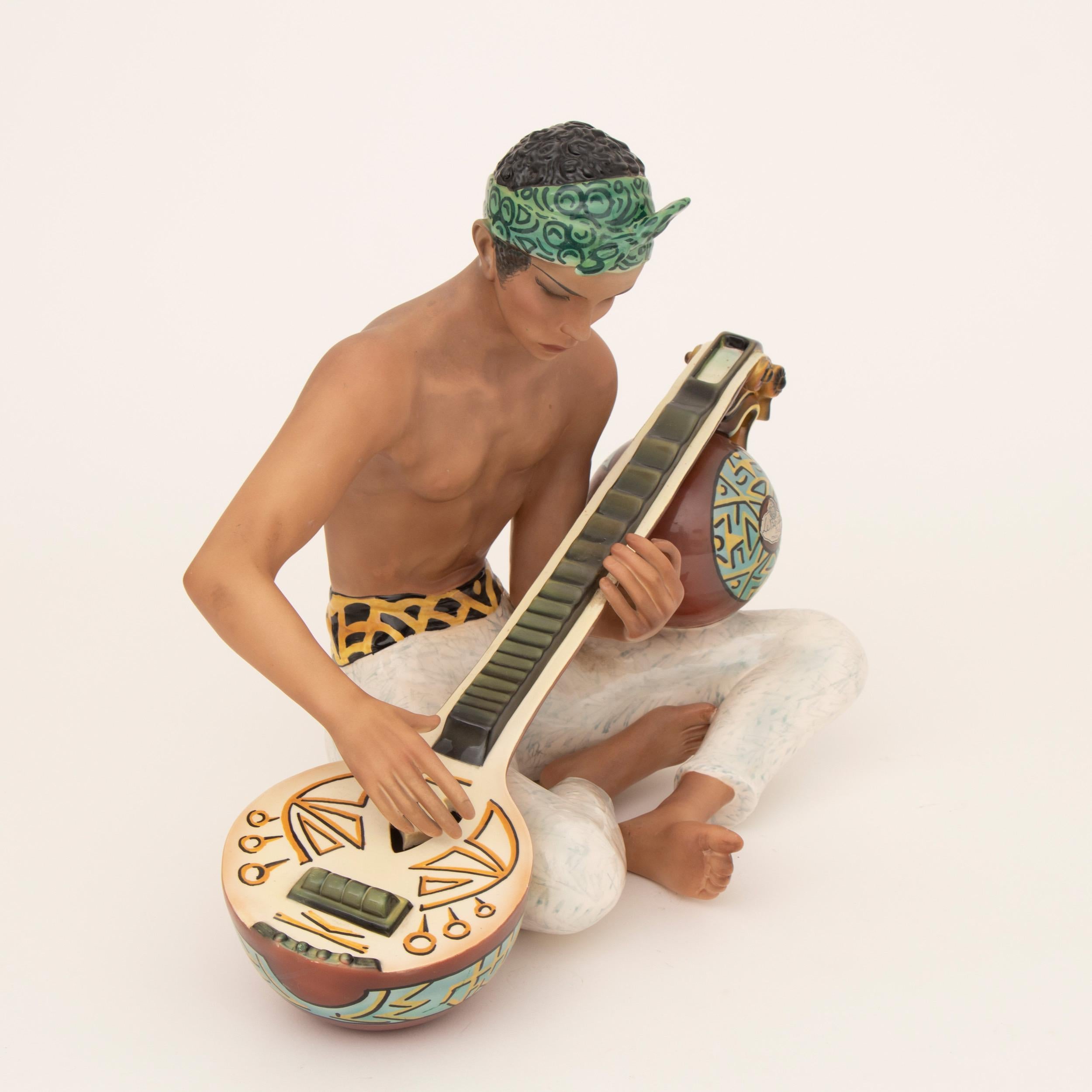 An exquisite figure with contrasting matte and gloss glazes of an Indonesian boy playing a sitar and dressed in white pants with a printed belt, wearing a patterned kerchief.
Measures: H 39cm W 48cm D 30cm
Italy circa 1933

Clelia Bertetti
