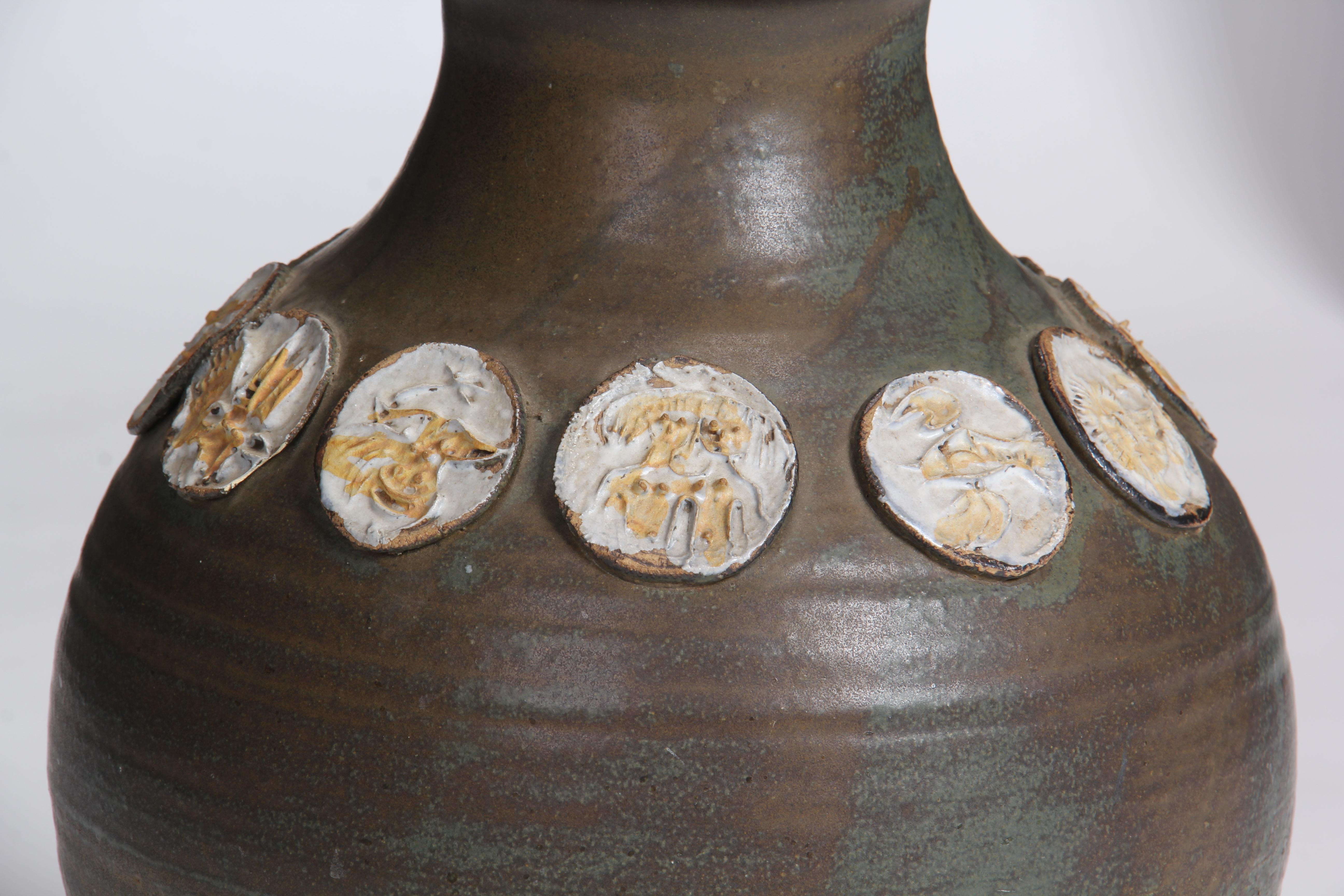 A Mid-Century Modern vase with hues of blue, brown and green encircled with ceramic coins representing the zodiac. Signed by artist. Made in Italy, circa 1960s.