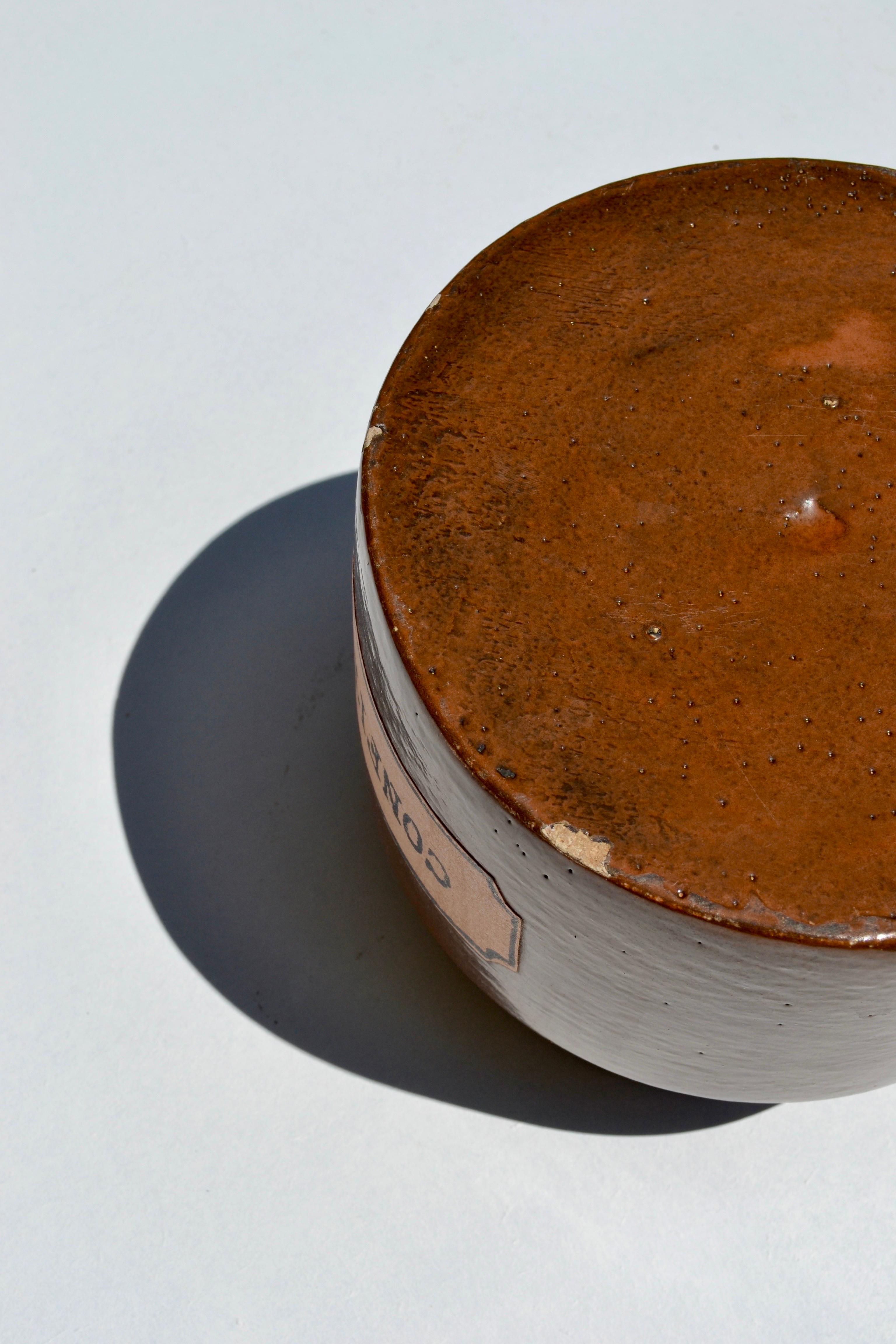 Un raffinato vaso cilindrico in ceramica con un colletto stretto, realizzato da Mado Jolain e prodotto per la boutique-galleria d'avanguardia di Benoît Guyot a Lione all'inizio degli anni Sessanta. Realizzato con uno smalto nero-marrone profondo e