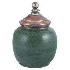 Ceramic jar glazed in green hues. With a brass and bronze lid.