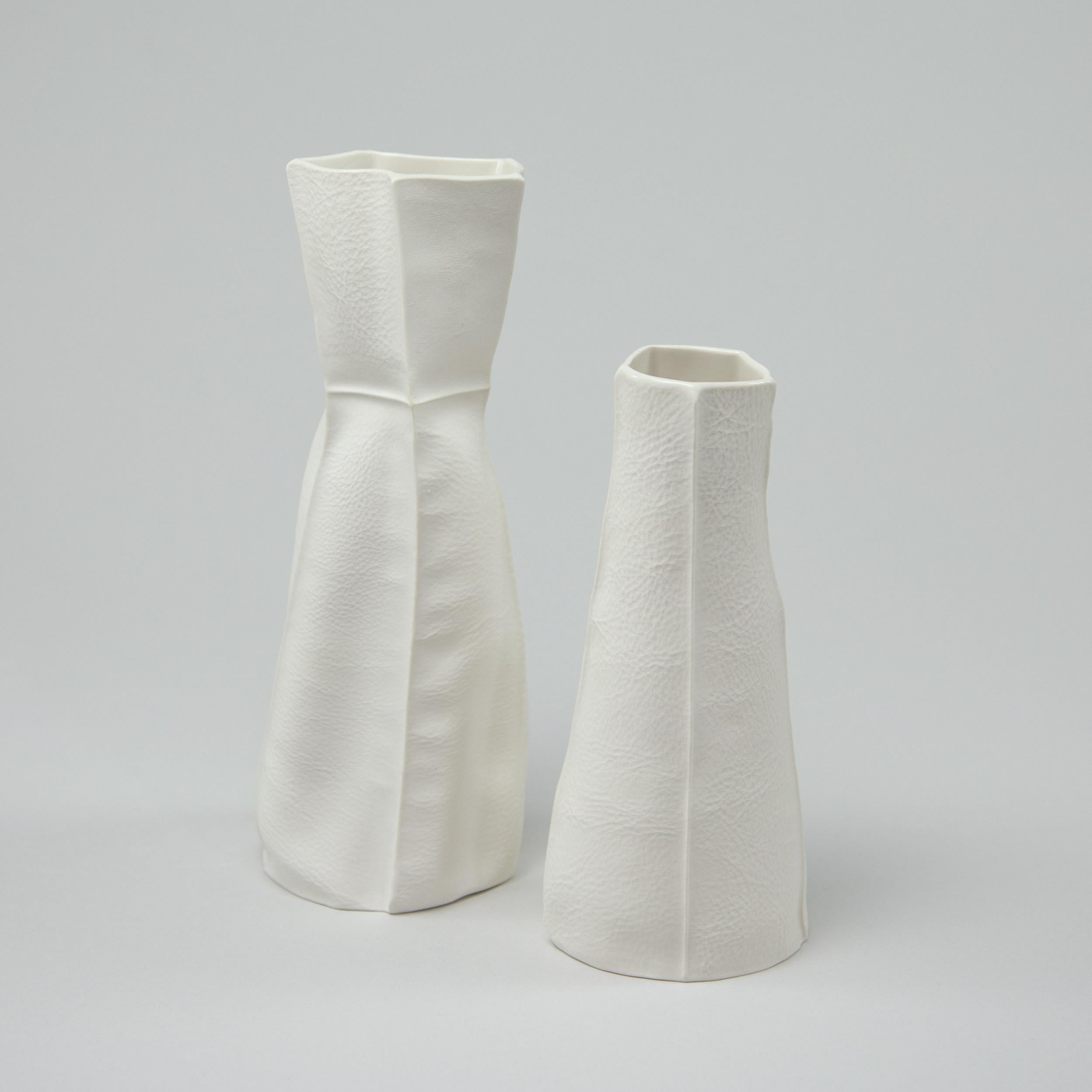 Paire de vases en porcelaine, tactiles et organiques, avec une surface extérieure texturée en cuir et un intérieur émaillé transparent. En raison du processus de production, chaque article est unique. L'ensemble comprend un vase moyen et un petit