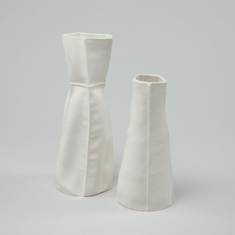 A pair of tactile and organic porcelain vases with leather textured exterior surface and clear glazed interior. As a result of the production process each item is one-of-a-kind. Set includes one medium vase and one small vase. 

Use individually