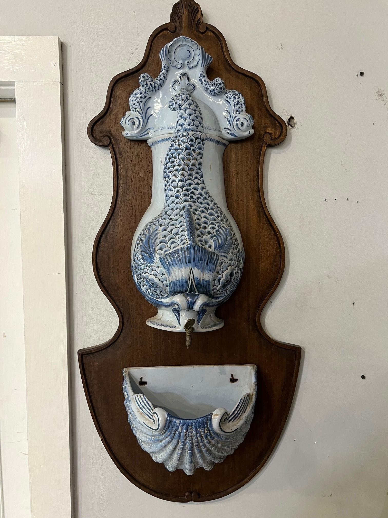A fabulous vintage ceramic wall fountain from the 1970s on a wood panel. This is a great indoor three piece fountain, lava bowl with spigot in the shape of a Koi fish, lid and spill basin. I believe this was imported in from Italy and sold in