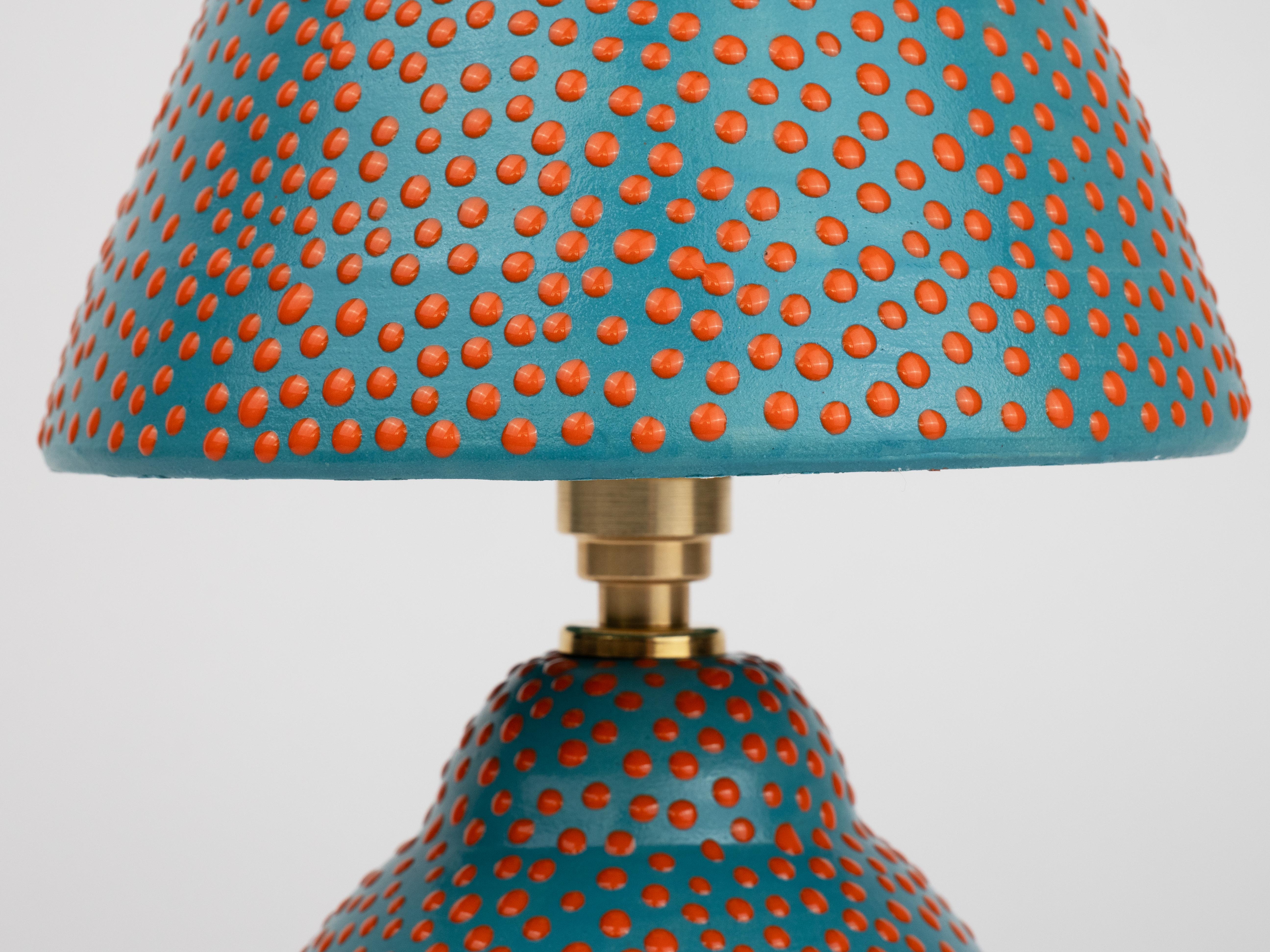 Diese bezaubernde Tischleuchte mit ihrer verspielten gepunkteten Struktur und der satinierten Glasur, die das Licht wunderschön einfängt, bringt Licht in Ihren Raum. Mit ihrem einzigartigen handgefertigten Design bringt diese Lampe einen Hauch von