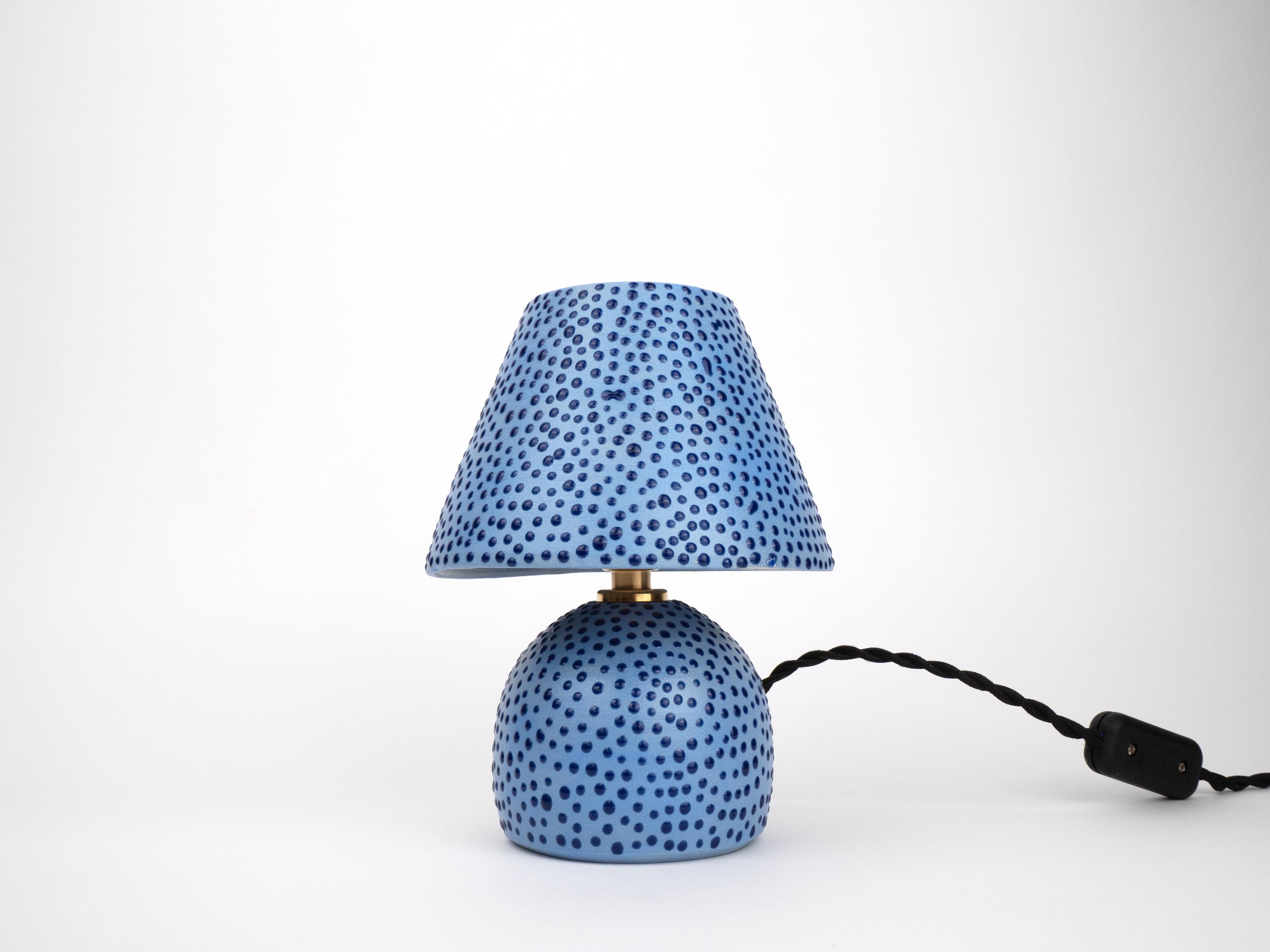 Illuminez votre espace avec cette charmante petite lampe, dotée d'une texture pointillée ludique et d'un émail satiné qui capte magnifiquement la lumière. Avec son design artisanal unique, cette lampe apportera une touche de fantaisie et de chaleur