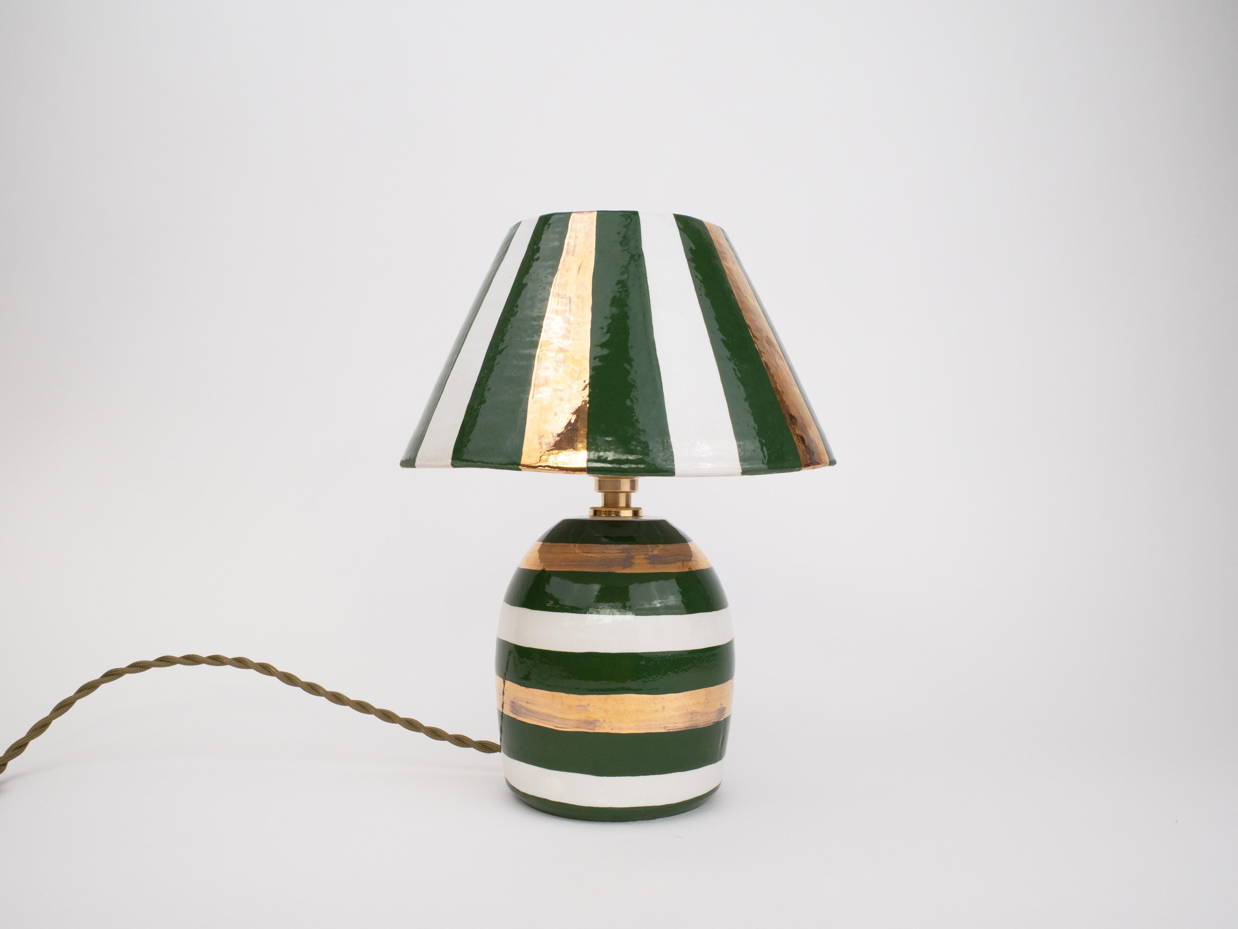 Bold, glossy, and a touch glam - this handcrafted ceramic lamp features white, deep green and 24k gold stripes. With its shiny finish and artisanal charm, it is a statement piece that will be sure to light up any decor.

Bulb is included
Bulb