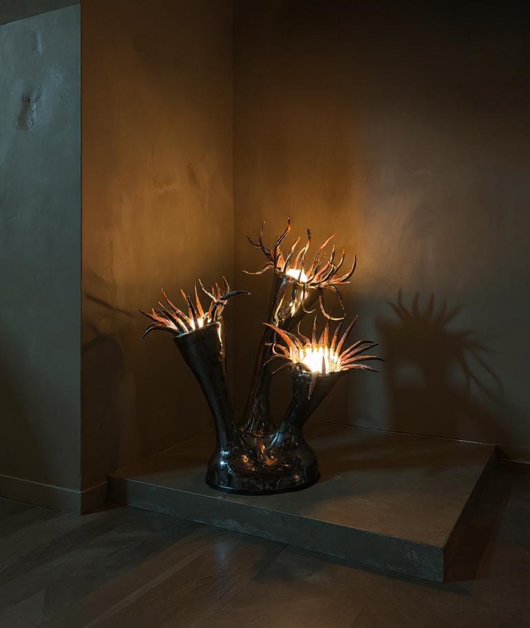 A striking sculptural lamp hand-built from clay and finished with a high-gloss glaze. Each organic form branches upward like a blooming sea creature, with light emanating from within its spiked crown. Equal parts lighting and art object, this piece