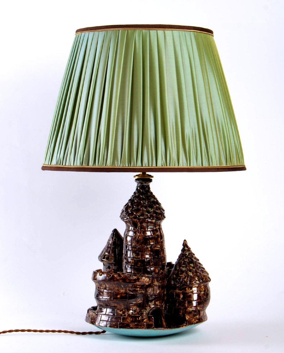 Lovely and very original lamp with a brown ceramic foot punctuated with touches of water green representing a medieval castle.

This magnificent lamp base is enhanced by a sumptuous pleated shade in changing water green silk, made in a traditional