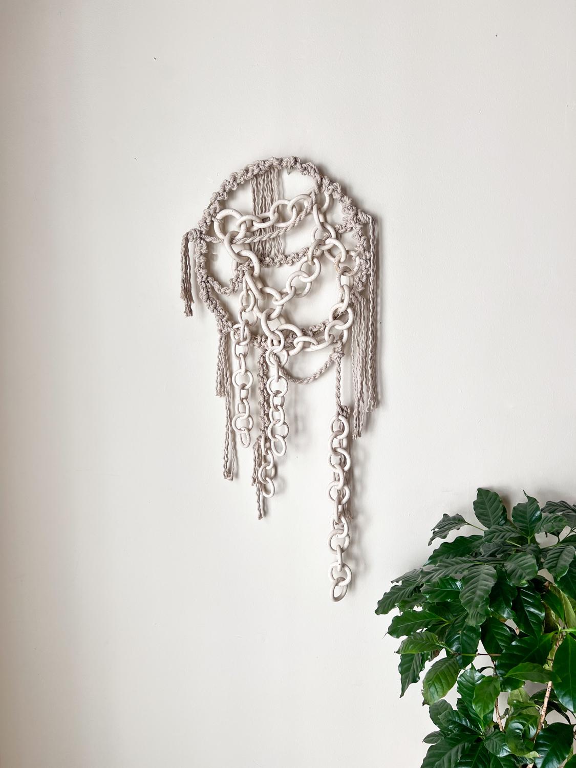 This eye-catching wall hanging adds a nomadic feel to any room. Created through a hand-intensive process of linking hand built stoneware rings of different sizes, this wall hanging is a dynamic decoration for an eclectic bedroom or living room.