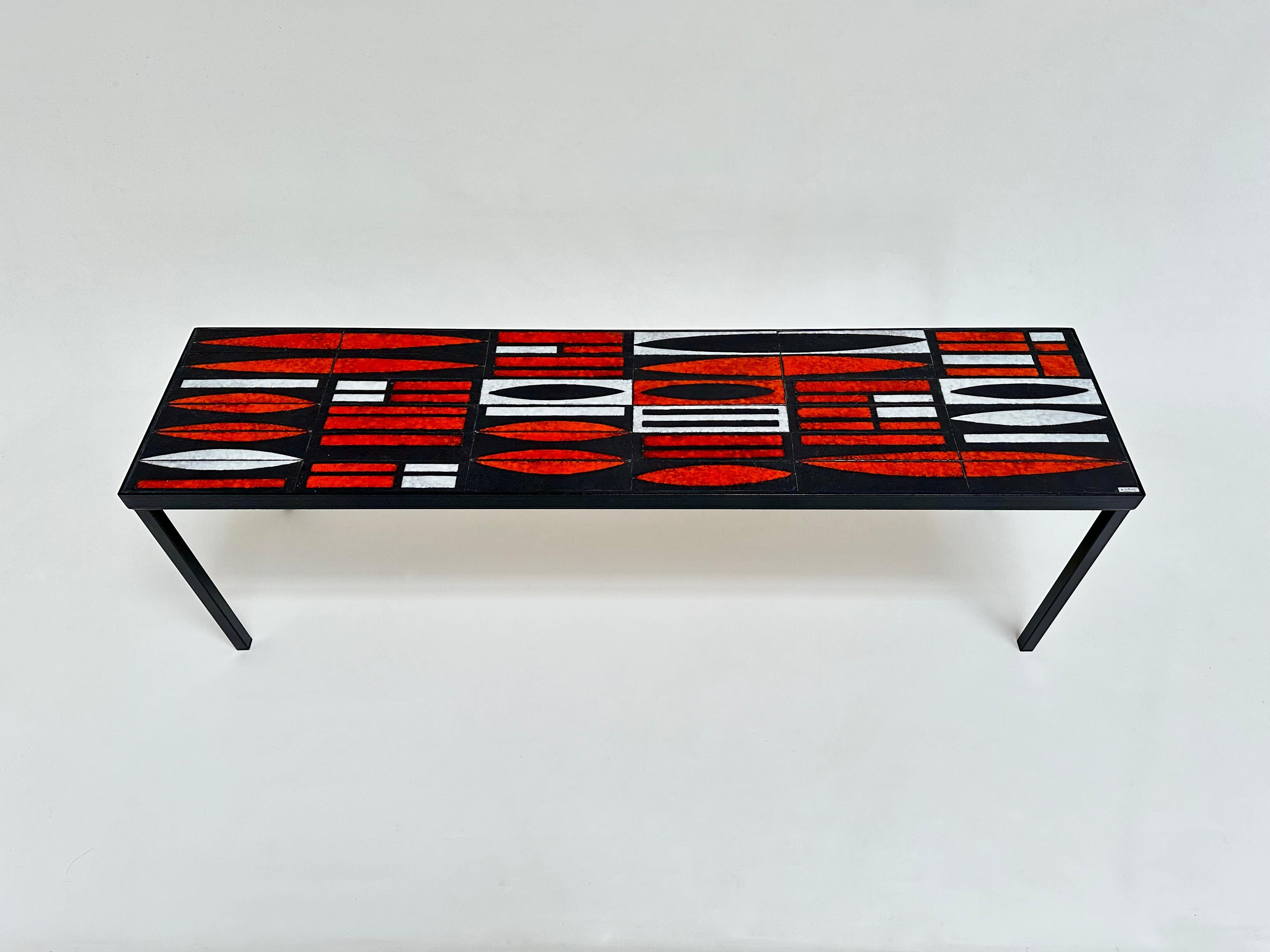 Black hammered ceramic tiles with rhythmic drawings realised in satin white ans shiny red glazes executed with the paraffin reserve technic which made the artist's reputation since the early 1950s.
A completely exceptional table in its very narrow