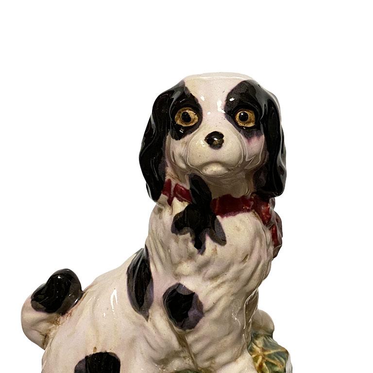 A pair of classical English style King Cavalier dog bookends. Created from ceramic, this pair depicts two dogs in white with black spots. Each wears a red collar and stands upon a herringbone green ball with faux bamboo detail. 

Overall