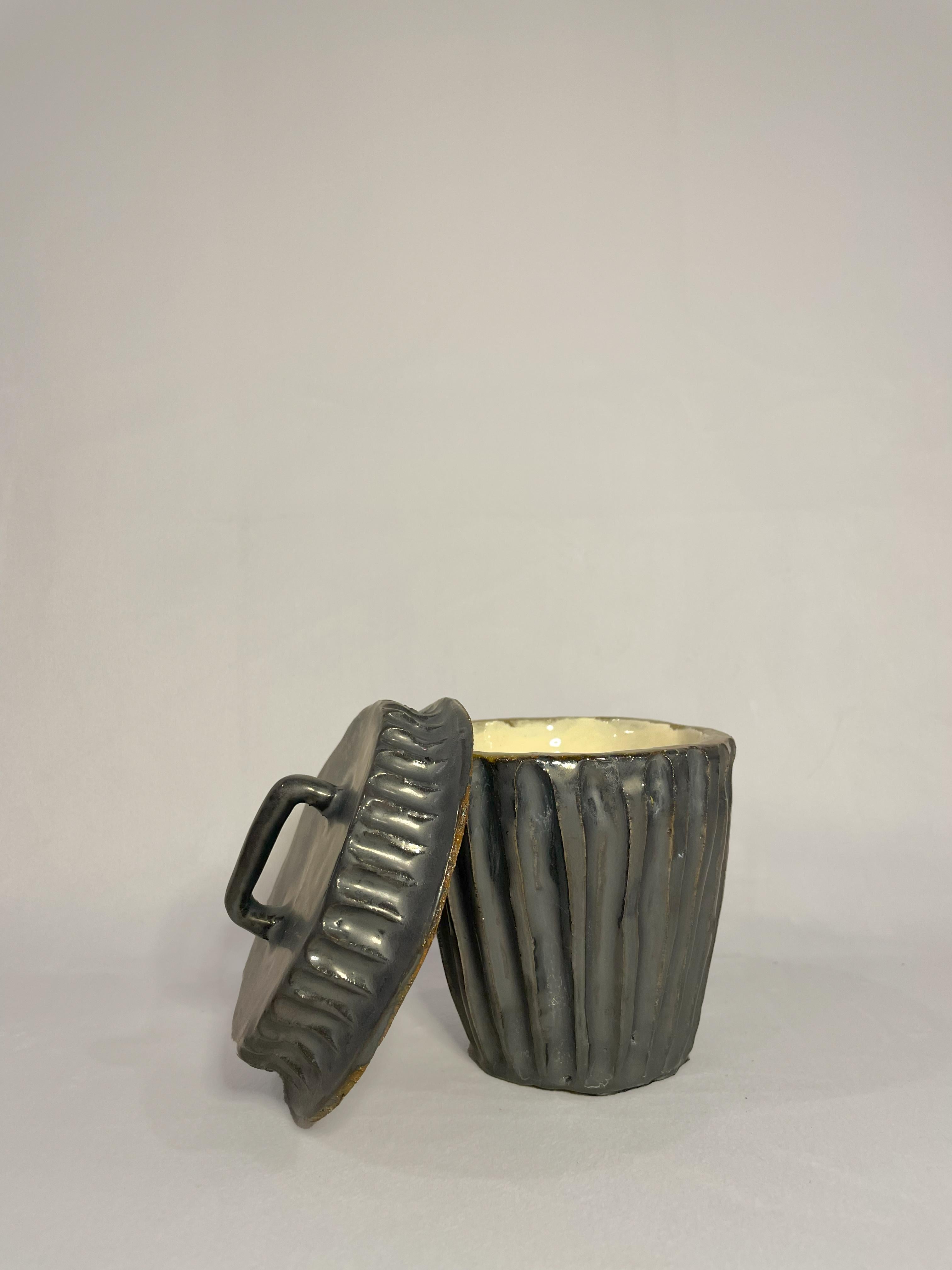 This delightful miniature trash can captures the essence of a traditional metal trash can with a touch of artistic flair. This small vessel exudes character and whimsy, making it an endearing addition to any space. 

A metallic glaze mimics the