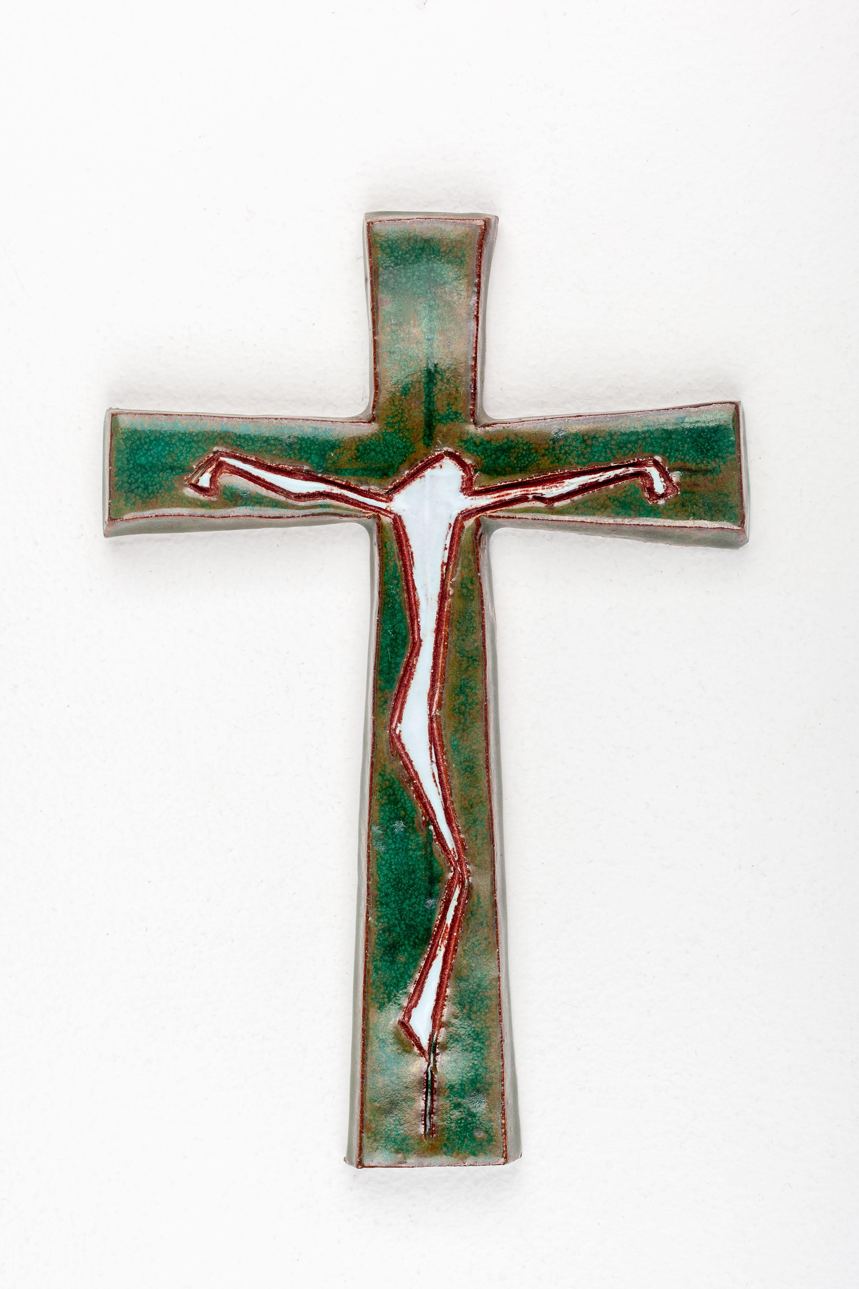This striking mid-century modern ceramic wall cross is a remarkable example of European studio pottery from the 20th century. The piece is a harmonious fusion of spiritual symbolism and modernist aesthetic. The figure of Christ is abstracted to