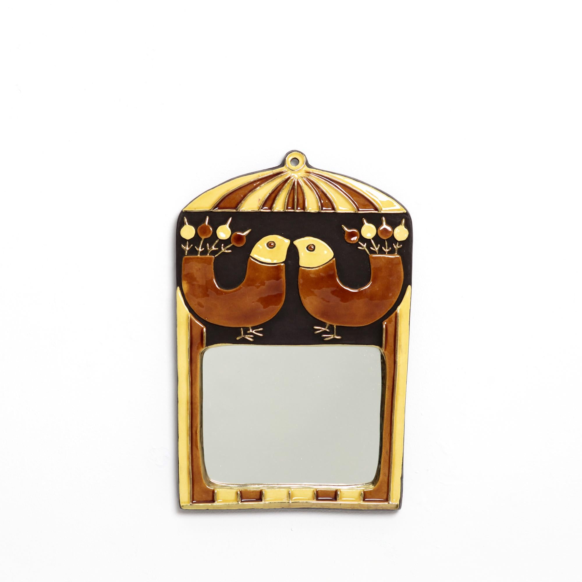 A wall mirror designed in the 1960s, fancyfully decorated with a cracked gold outline framing the representation of 2 birds in straw yellow and caramel brown and gold enamel, the decoration treated in light relief. Original ice, felt back. H. 31.5