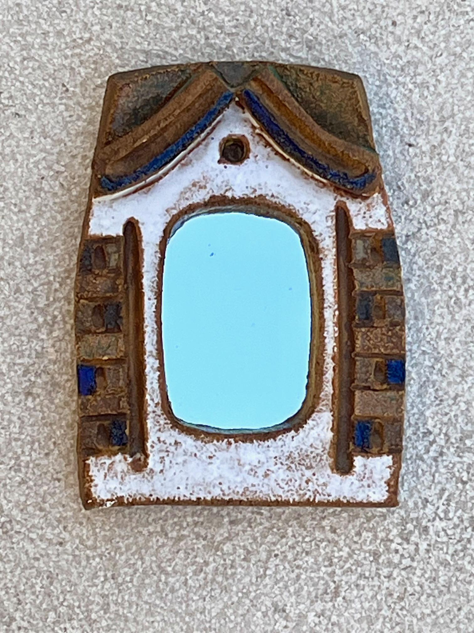 Miroir en céramique.
cadre en céramique partiellement émaillé dans des tons de  blanc, bleu et vert
Forme de fenêtre, avec fronton au sommet
 Signé au dos 