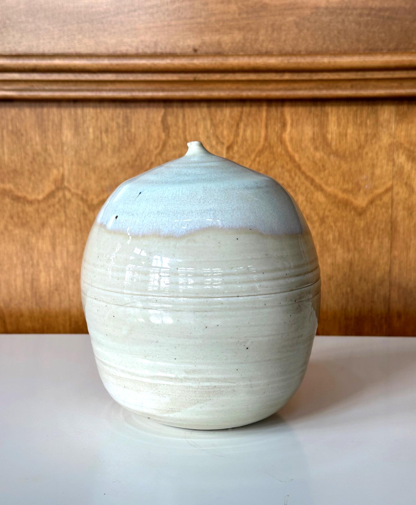 Un pot en céramique de forme fermée avec hochet de l'artiste américano-japonaise Toshiko Takaezu (américaine, 1922 - 2011). 
L'histoire : Dans les années 1980, la potière Lola RAE a invité Toshika dans son studio de céramique et son four à Ojai, en
