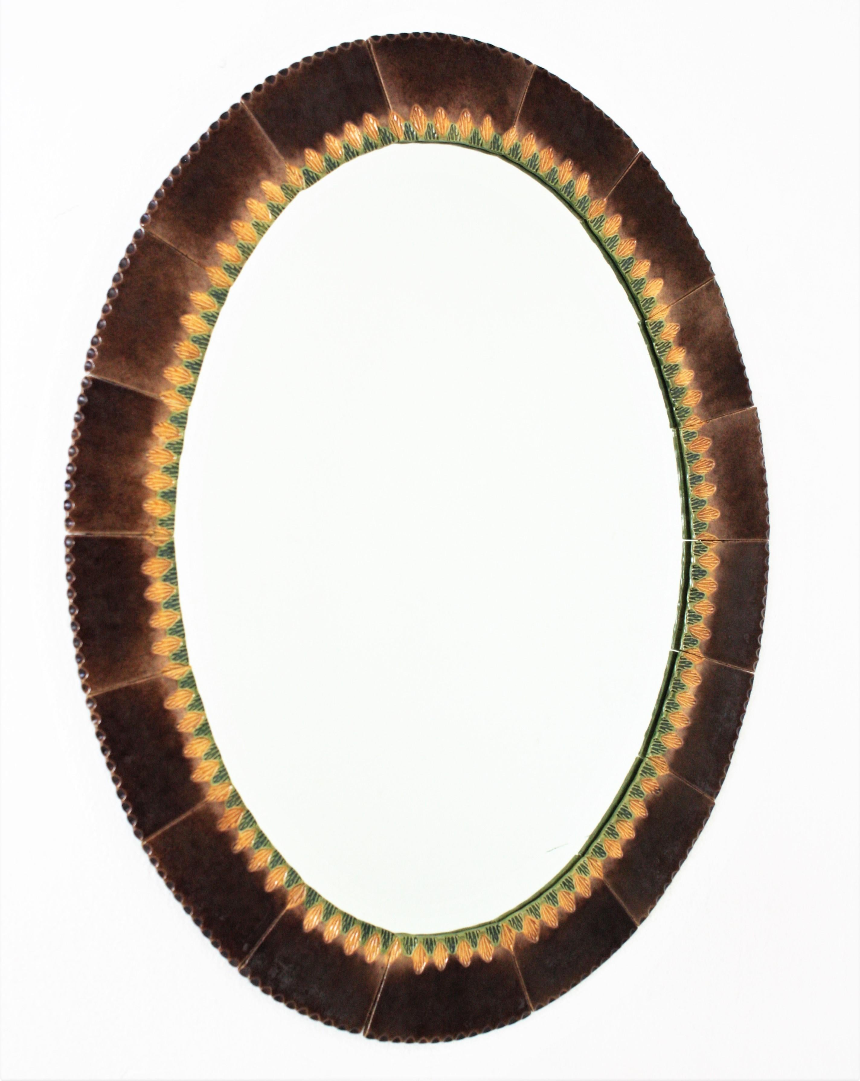 Eye-catching large ceramic mirror. Maufactured in Spain, 1960s.
Oval Shape and large glass mirror surface.
The frame is made of glazed ceramic tiles in shades of brown. A decorative pattern in green an yellow surrounds the glass mirror.
This wall