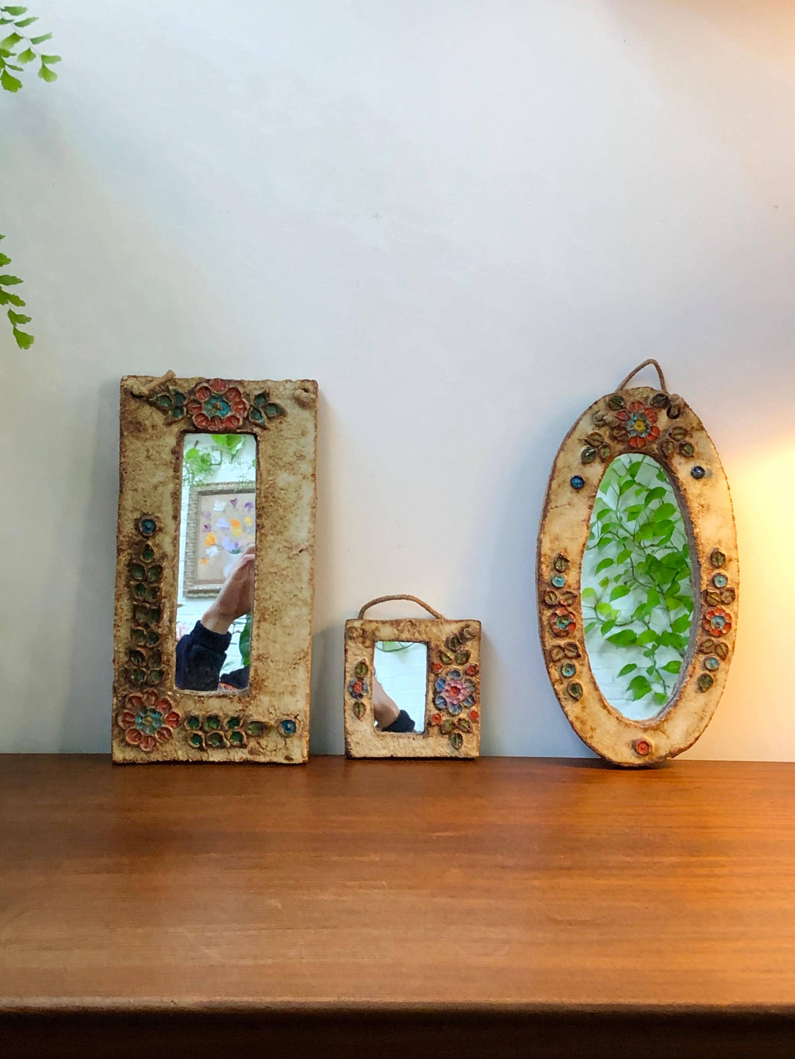 Ceramic flower-motif wall mirror with glazed leaves attributed to La Roue, Vallauris, France (circa 1960s). A charming, decorative small mirror with rustic but colourful details surrounding the oval mirror. In good vintage condition showing