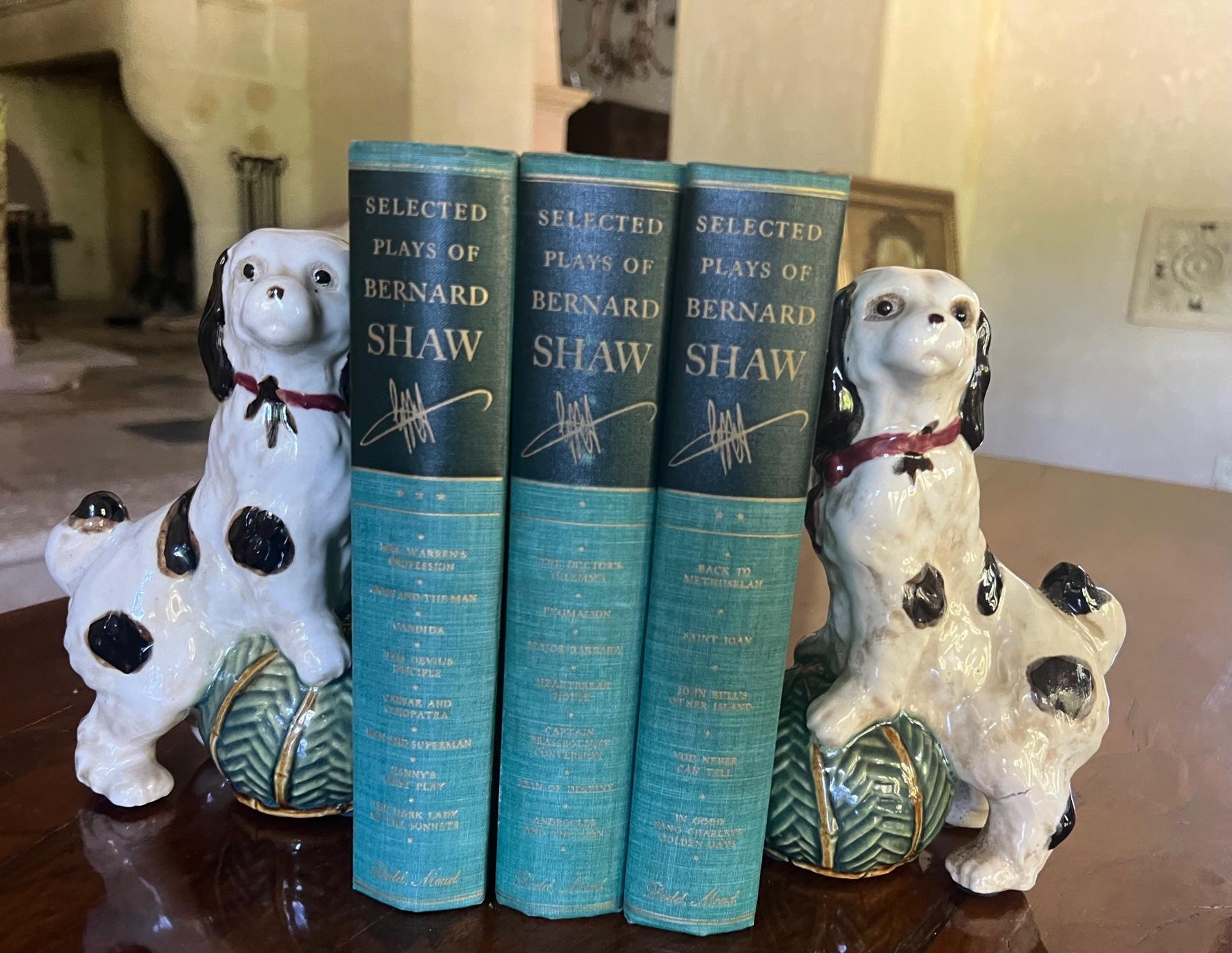 A pair of classical English style King Cavalier ceramic dog bookends. The pair are white with black spots. Each wears a red collar and leans a herringbone green ball with faux bamboo detail. 

Each dog measures: 4.5 