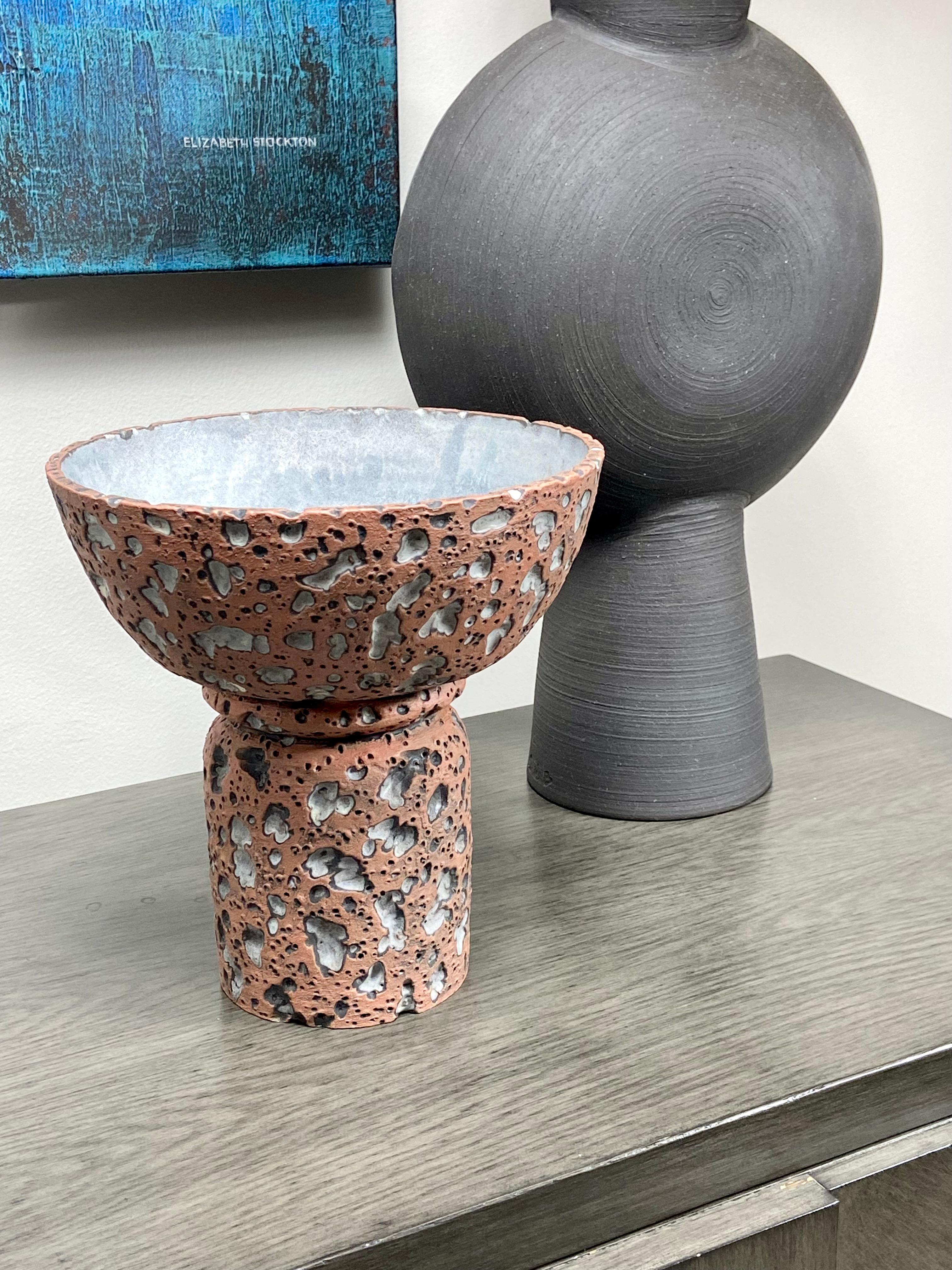 A stunning ceramic footed bowl in a lava glaze by Los Angeles based LGS Studio. This beautiful bowl is a great example of the intricacy of their work. It has Mid-Century inspired tactile lava glaze in a terracotta color with a contrasting smooth