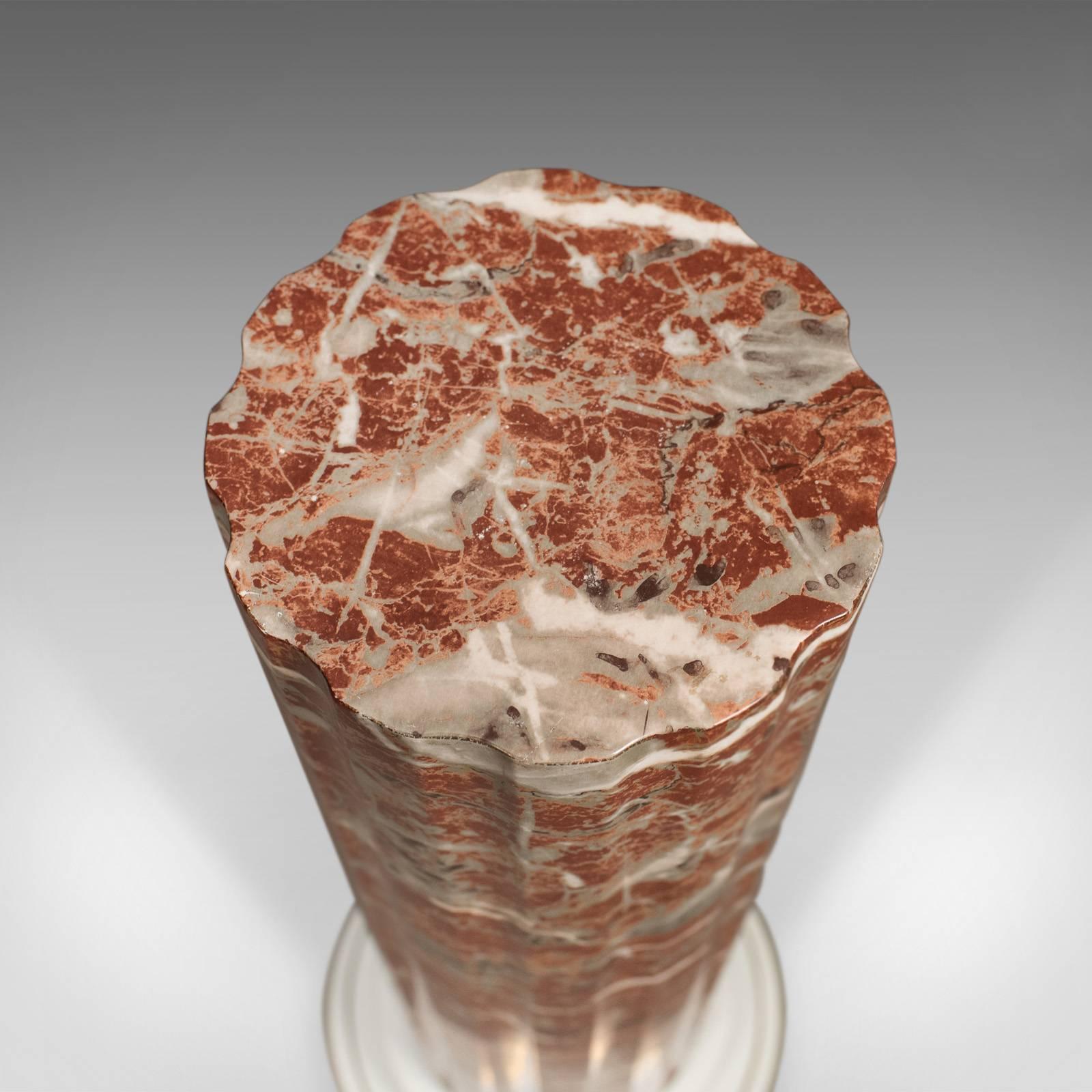 This is a ceramic pedestal with rouge marble effect finish, a late 20th century plant stand.

Standing in a broad white collared base
Gilt lined at the perimeter
Fluted column in classical taste
Astonishing rouge marble finish
Flat platform