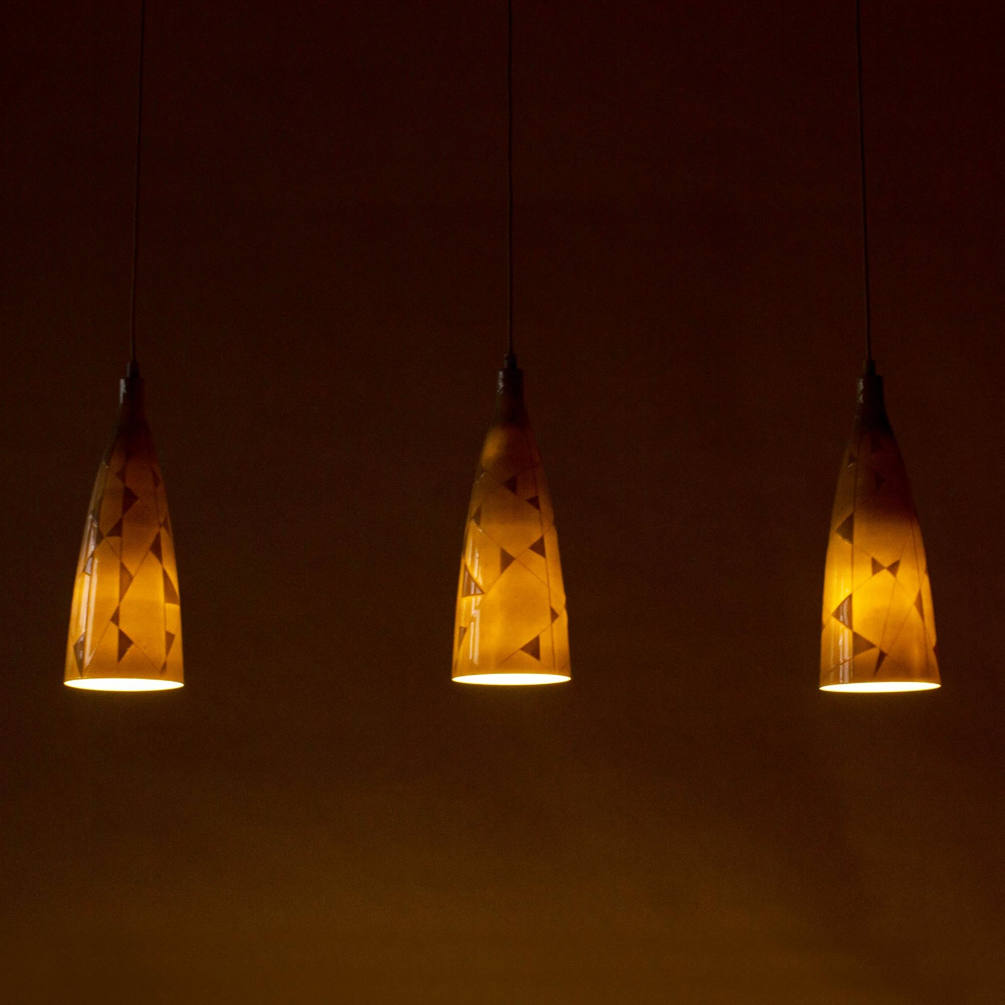 Ensemble de trois lampes suspendues en porcelaine d'os de Carl-Harry Stålhane. Conçue avec un motif graphique asymétrique qui varie en densité, créant un bel effet lorsqu'elle est éclairée.