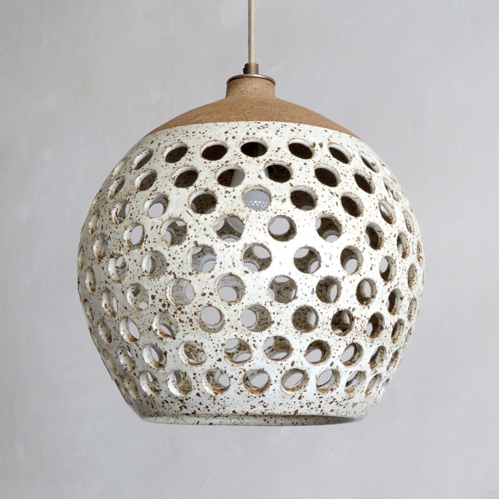 Wonderful ceramic pendant light No. L519, designed and handcrafted by Los Angeles based ceramicist Heather Levine. High fired stoneware with speckled matte white glaze on a cork colored clay body with decorative circles cut out to expose light in