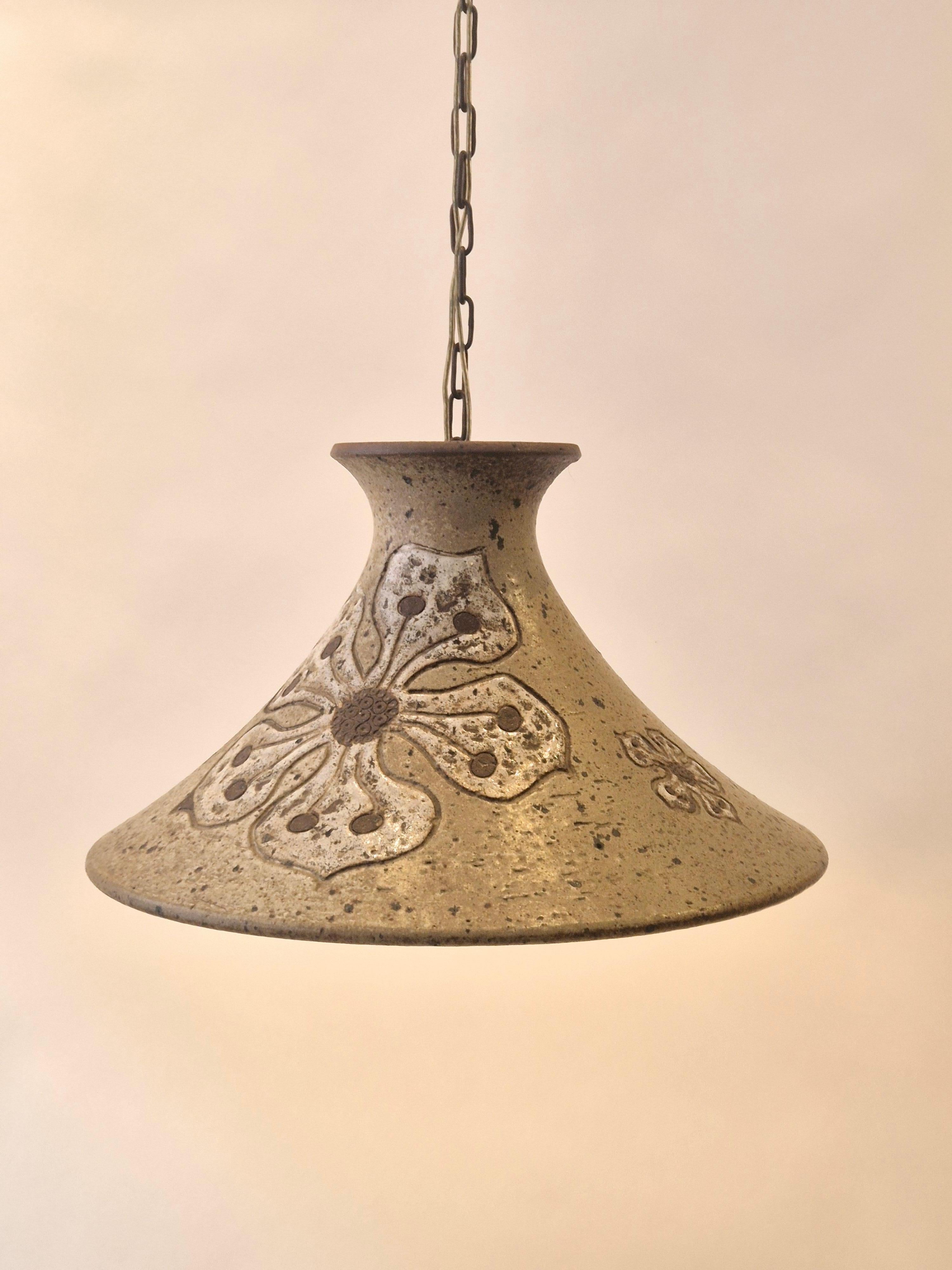 A rare stoneware pendant by danish ceramist Mette Lokke Stiil, 1960/70s. Glazed decor of flowers. 

Height excluding chain 42 cm. Total height 74 cm. In good condition. Ceiling cup with dent. 
